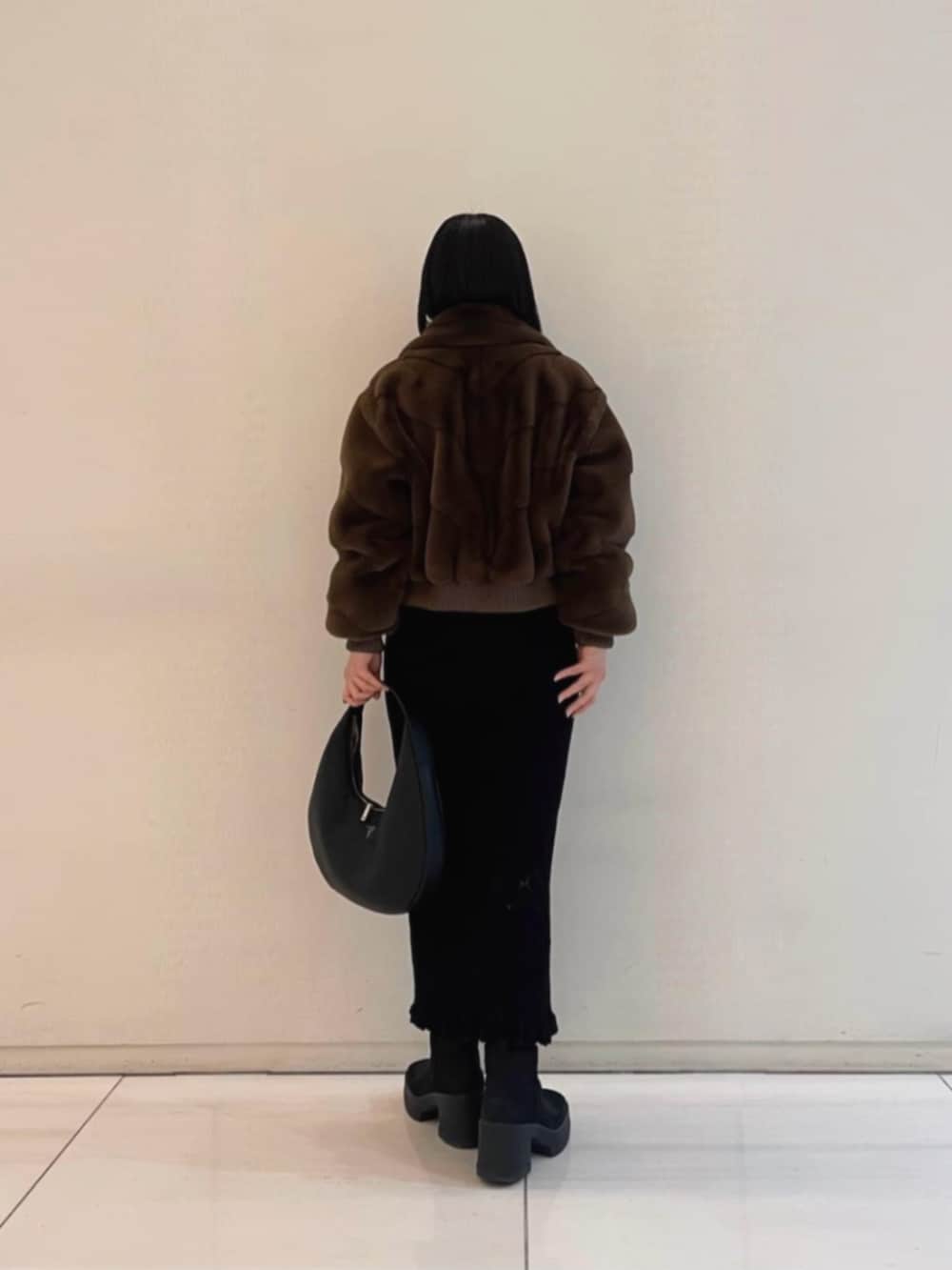 ブラック系のワンピース、ブラウン系のブルゾン、ブラック系のハンドバッグを着用したレディースの冬コーディネートの2枚目の写真