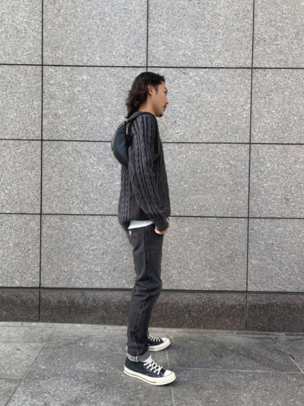 グレー系のデニムパンツ、ブラック系のショルダーバッグ、ブラック系のニット/セーターを着用したメンズの冬コーディネートの3枚目の写真