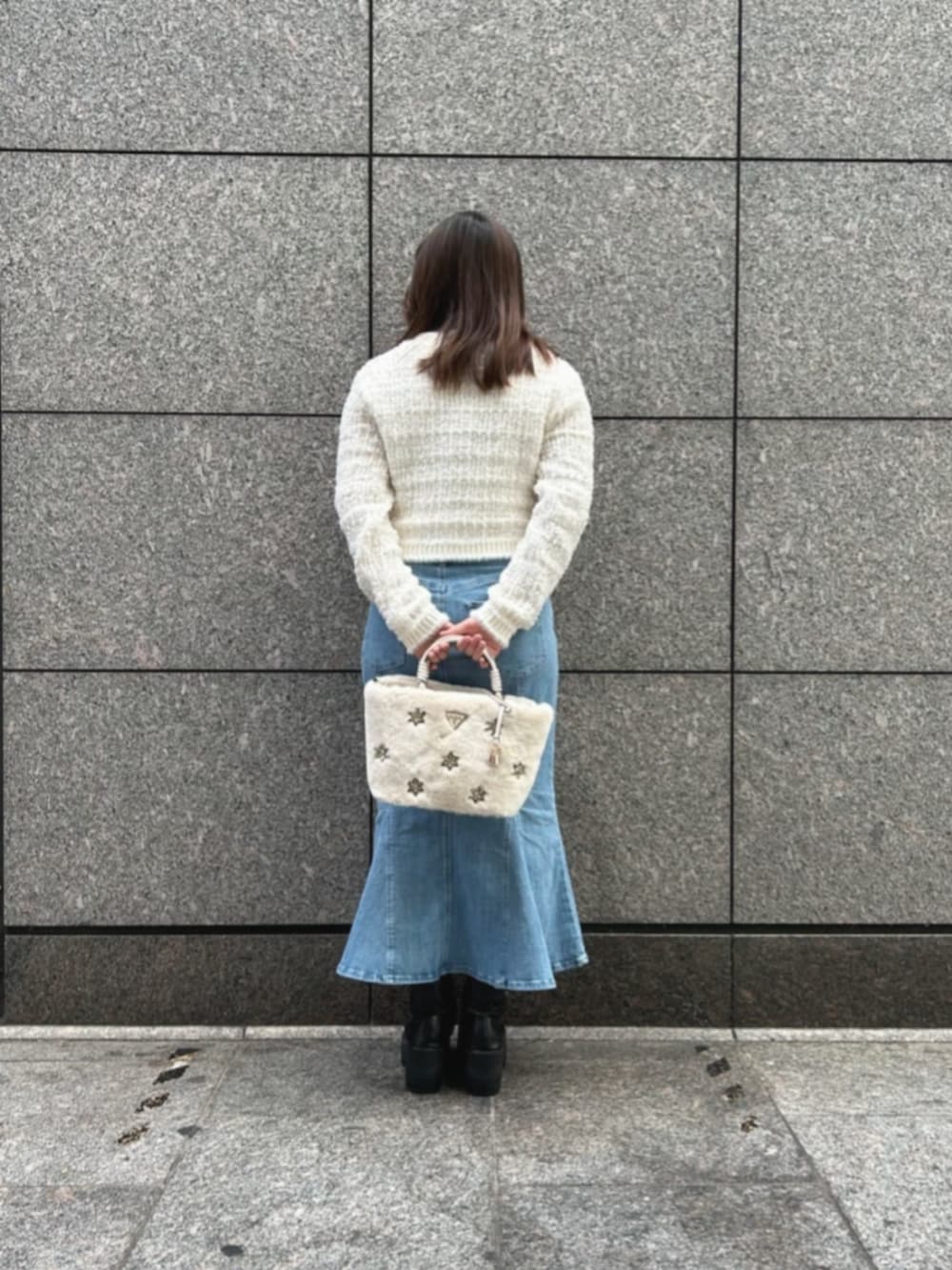 ブルー系のデニムスカート、ホワイト系のカーディガン/ボレロ、ホワイト系のショルダーバッグを着用したレディースの冬コーディネートの2枚目の写真