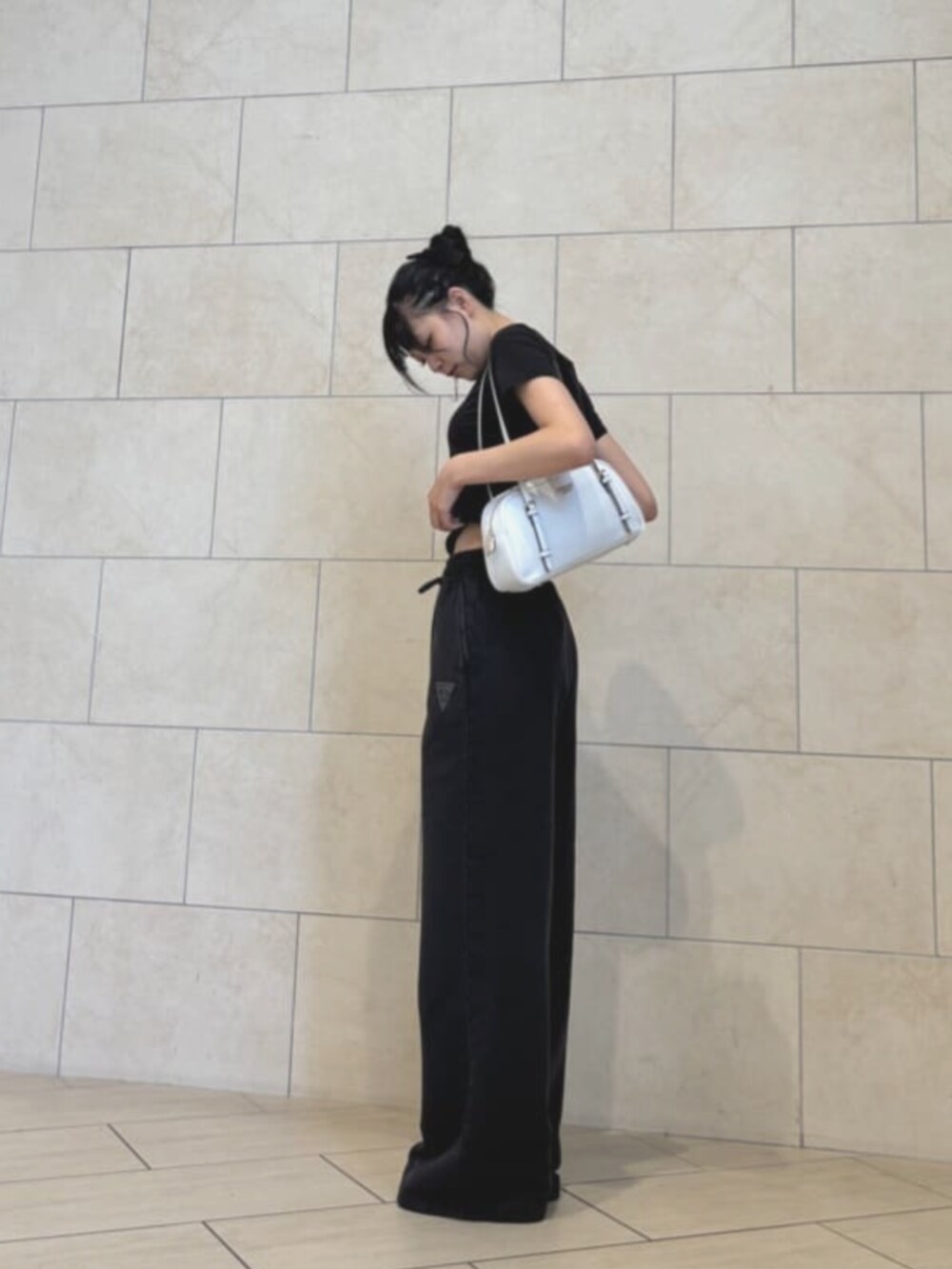 ブラック系のスウェットパンツ、ホワイト系のショルダーバッグ、ブラック系のTシャツ/カットソーを着用したレディースの夏コーディネートの2枚目の写真