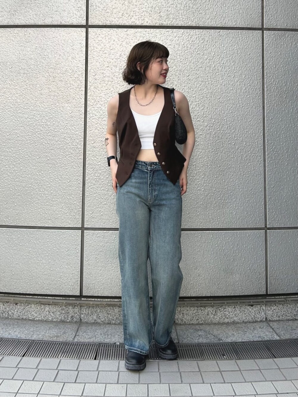 ブラウン系のベスト、ブルー系のデニムパンツ、ブラック系のハンドバッグを着用したレディースの夏コーディネートの4枚目の写真