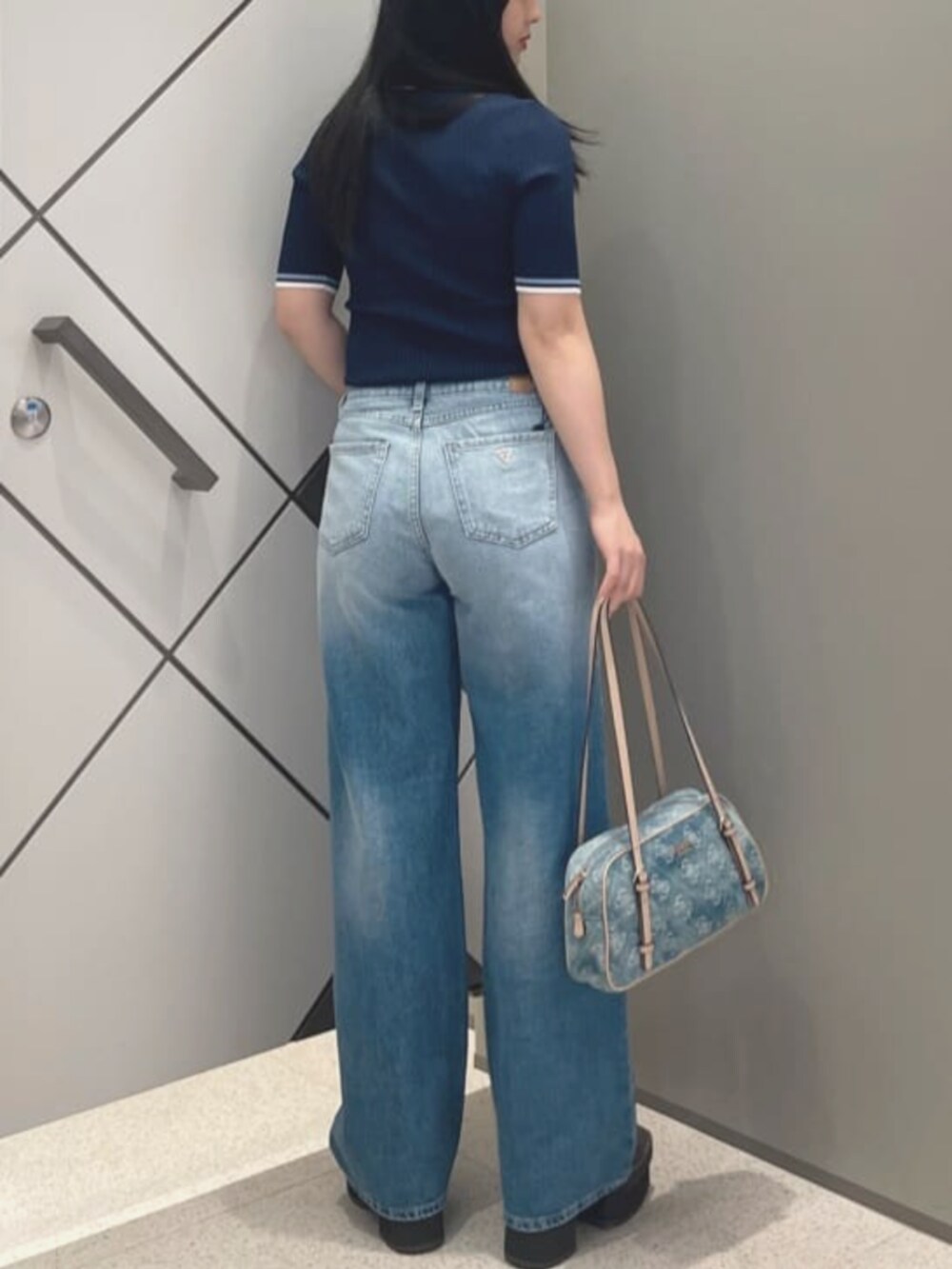 ブルー系のショルダーバッグ、ブルー系のポロシャツ、ブルー系のデニムパンツを着用したレディースの夏コーディネートの2枚目の写真