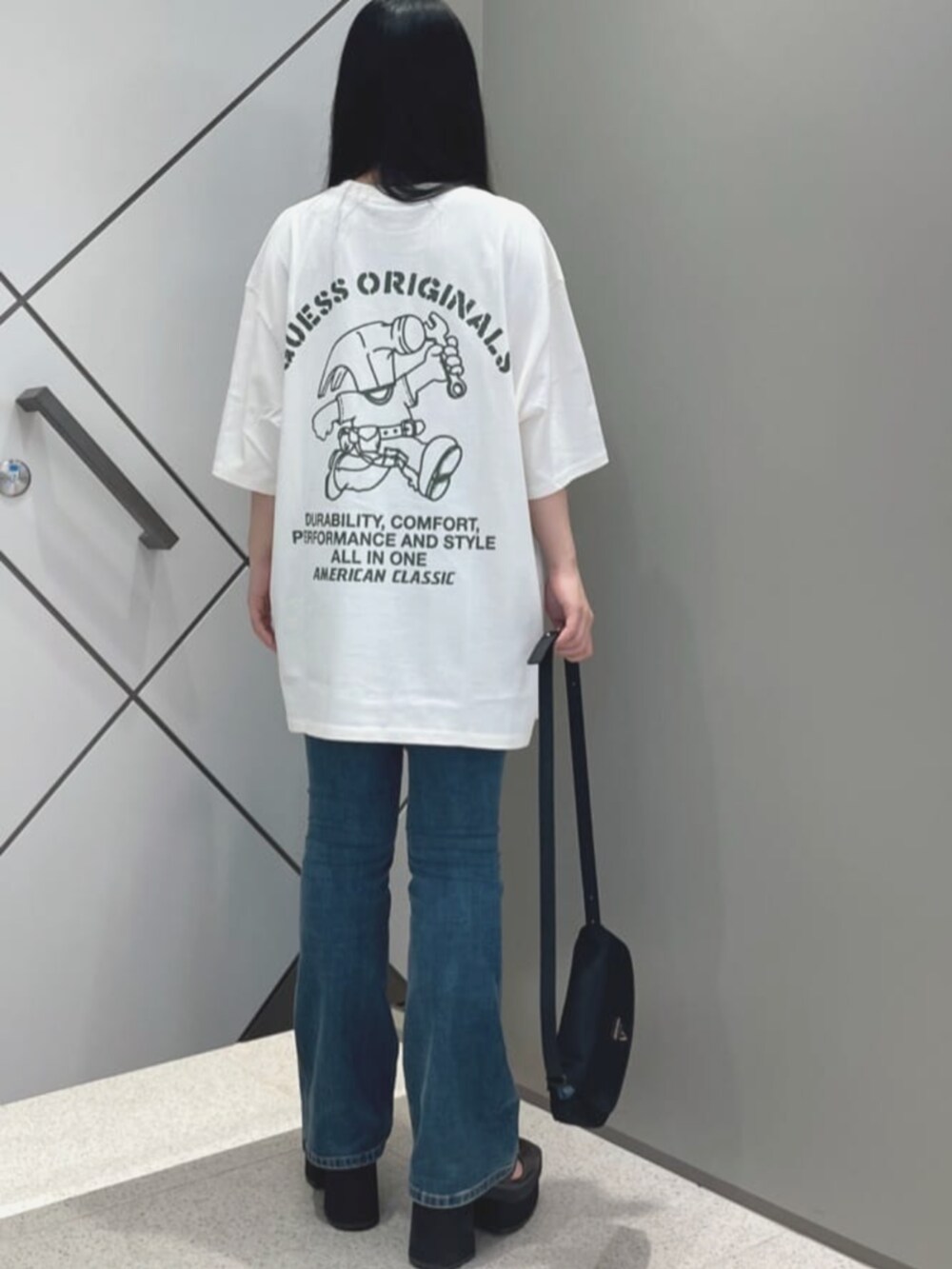 ブルー系のデニムパンツ、ブラック系のショルダーバッグ、ホワイト系のTシャツ/カットソーを着用したレディースの夏コーディネートの2枚目の写真