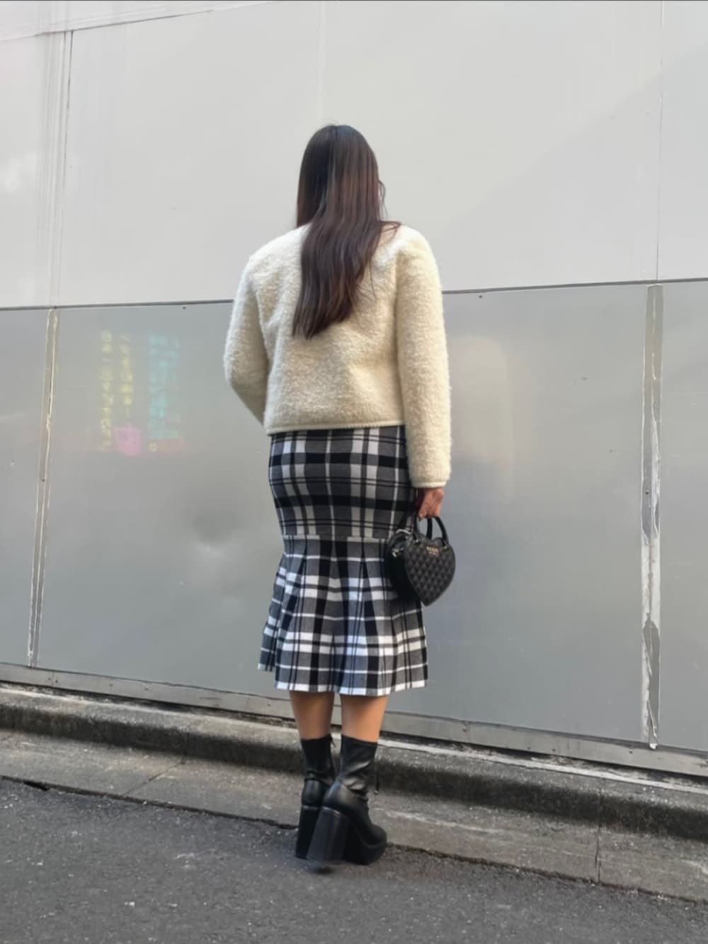 ブラック系のワンピース、ブラック系のショルダーバッグ、ホワイト系のノーカラージャケットを着用したレディースの冬コーディネートの2枚目の写真