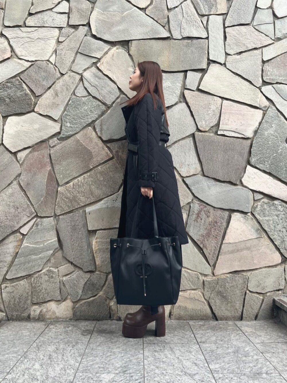 ブラック系のワンピース、ブラック系のトレンチコート、ブラック系のトートバッグを着用したレディースの秋コーディネートの3枚目の写真