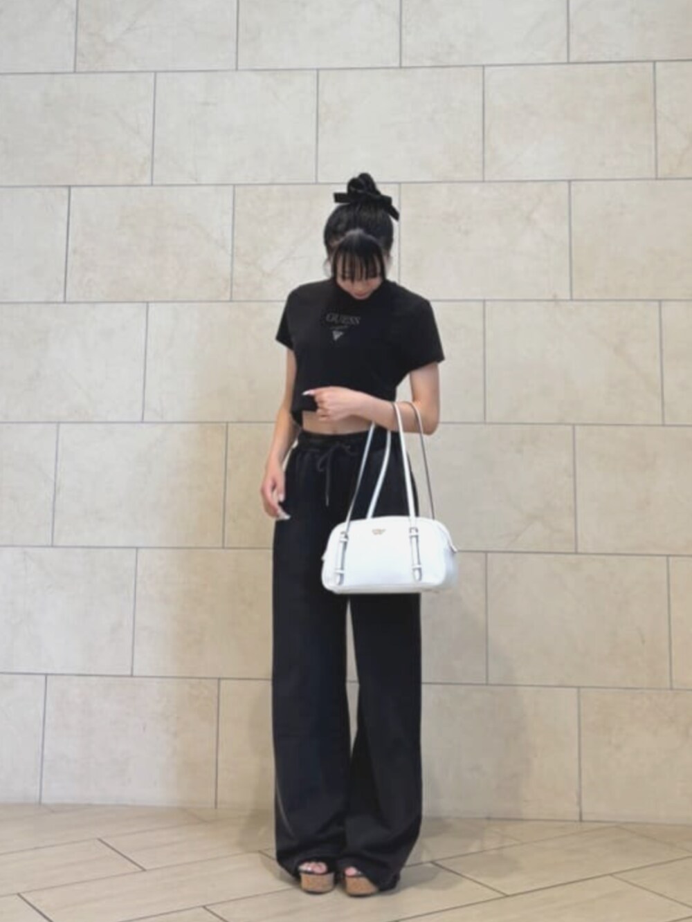 ブラック系のスウェットパンツ、ホワイト系のショルダーバッグ、ブラック系のTシャツ/カットソーを着用したレディースの夏コーディネートの3枚目の写真