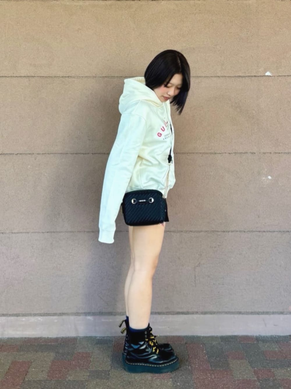 ブラック系のショルダーバッグ、ホワイト系のパーカーを着用したレディースの秋コーディネートの3枚目の写真