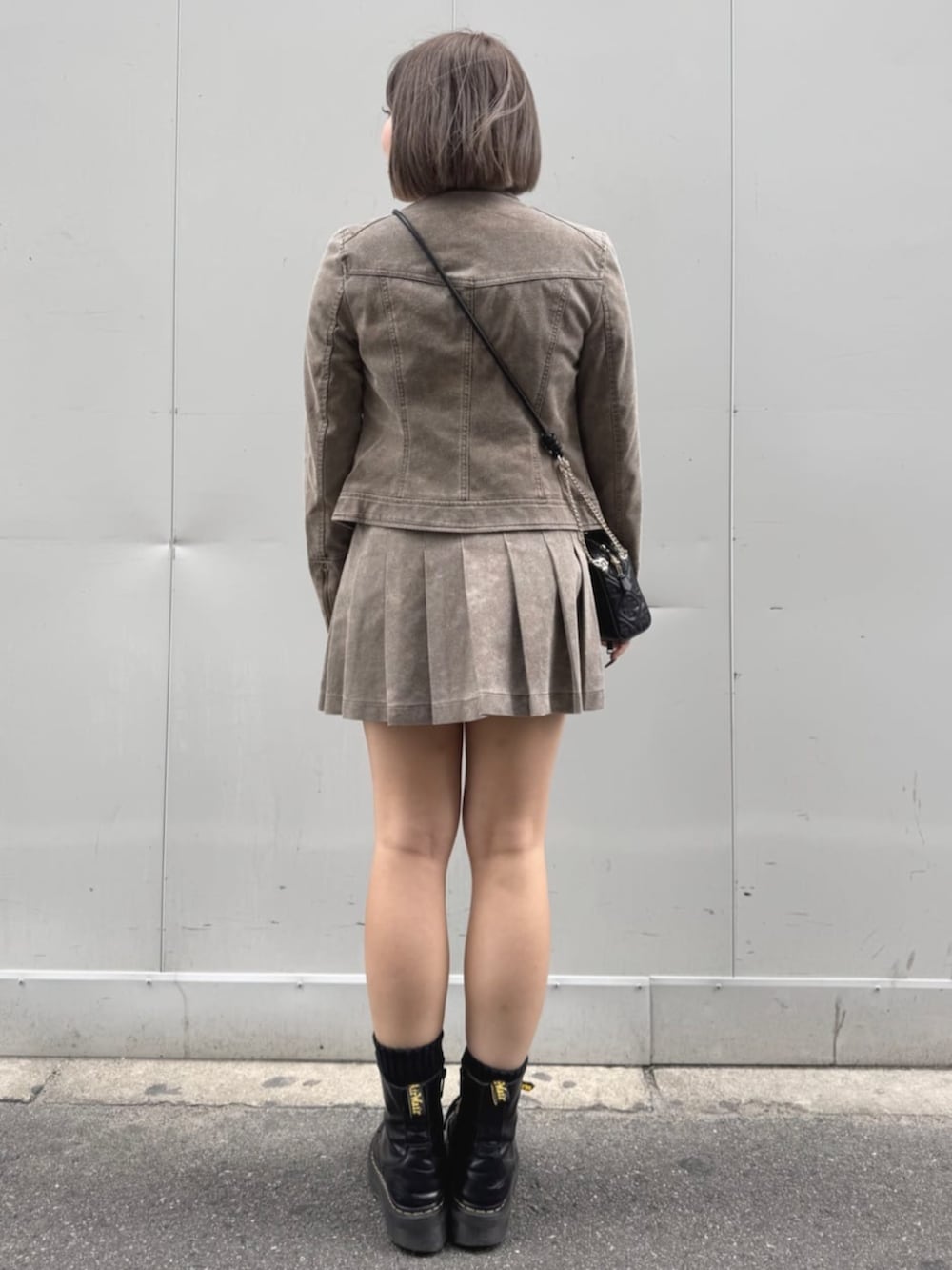 ベージュ系のノーカラージャケット、ベージュ系のスカート、ブラック系のニット/セーターを着用したレディースの秋コーディネートの2枚目の写真