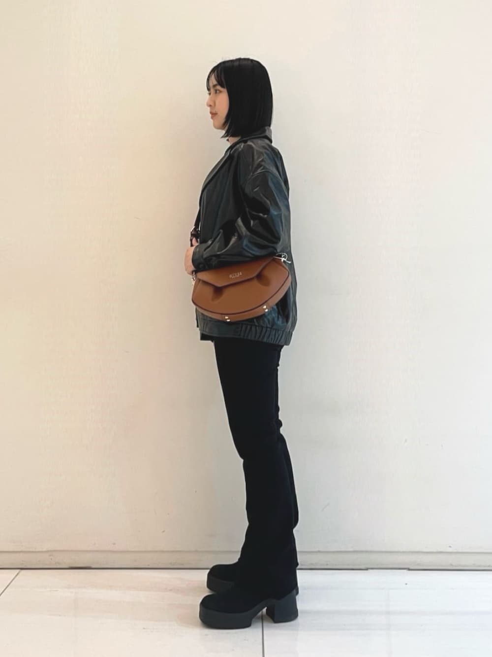 ブラック系のニット/セーター、ブラウン系のショルダーバッグ、ブラック系のカバーオールを着用したレディースの春コーディネートの4枚目の写真