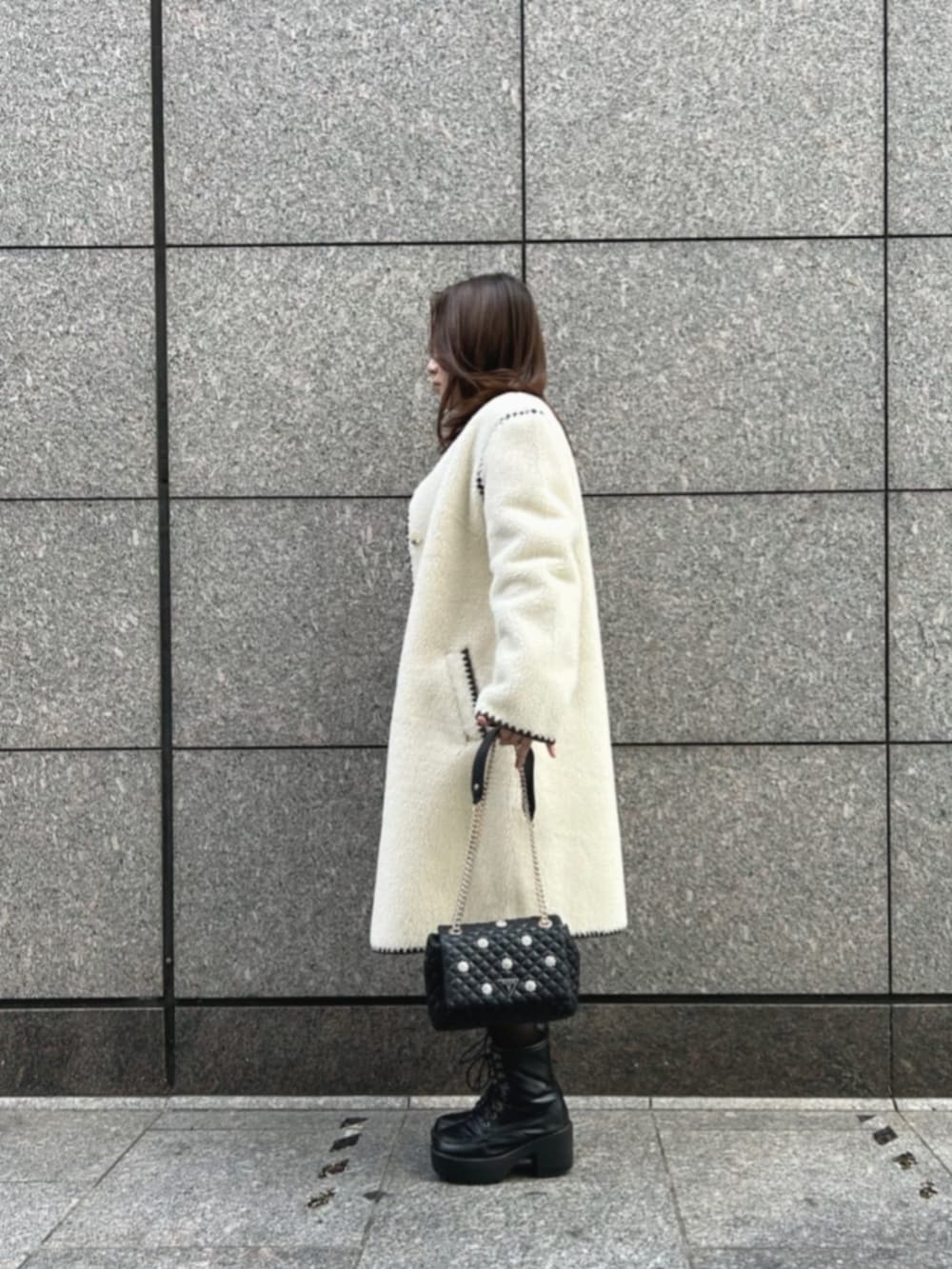 ブラウン系のワンピース、ブラック系のショルダーバッグ、ホワイト系のノーカラージャケットを着用したレディースの秋コーディネートの3枚目の写真