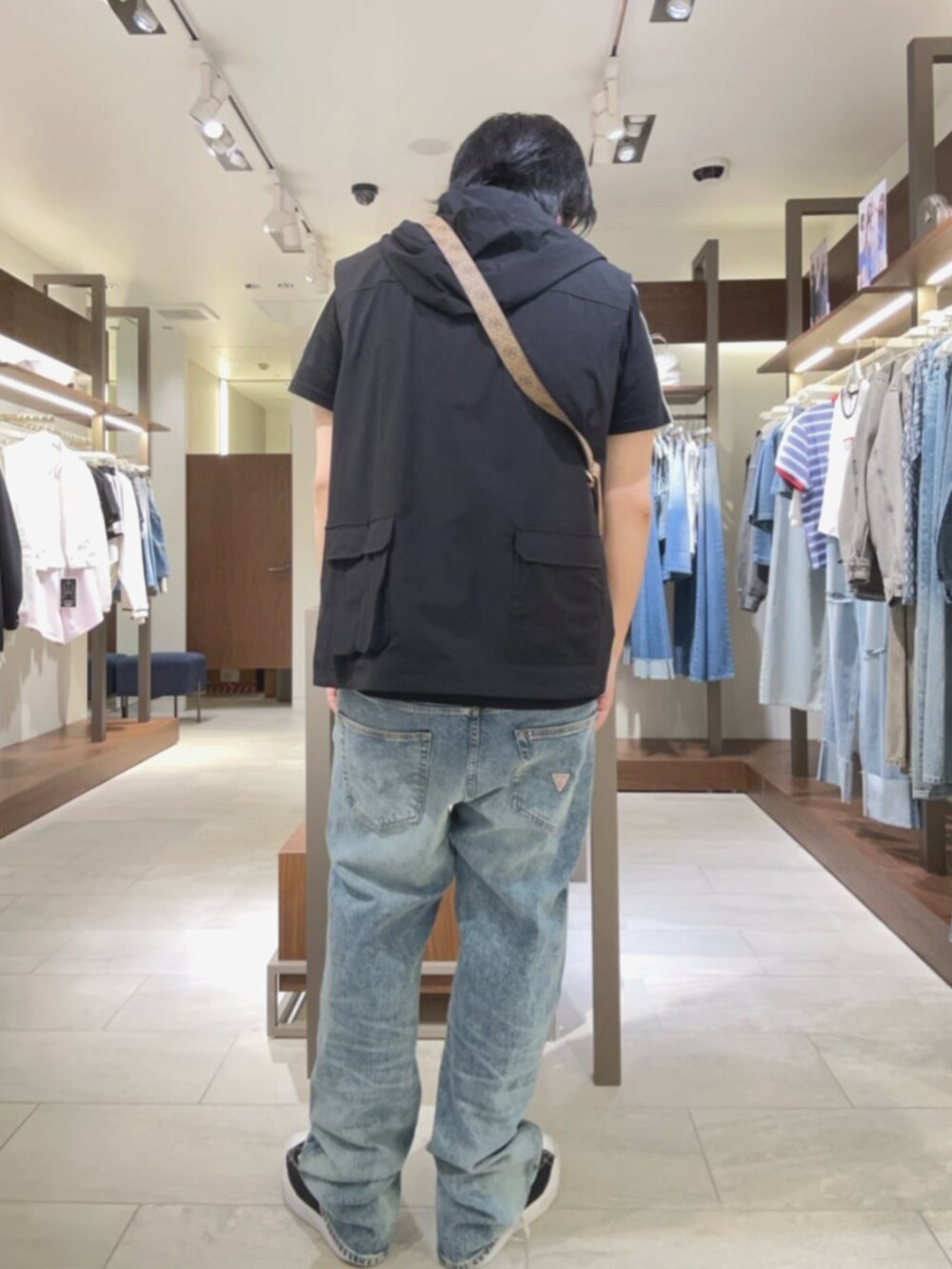 ベージュ系のショルダーバッグ、ブルー系のデニムパンツを着用したメンズの夏コーディネートの2枚目の写真