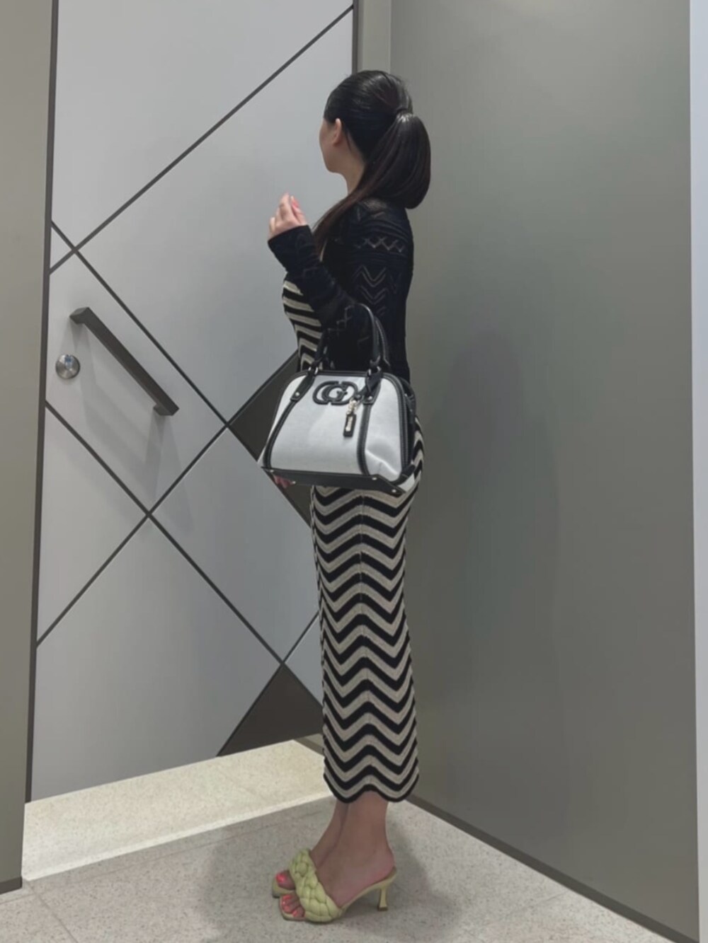 ブラック系のショルダーバッグ、ブラック系のカーディガン/ボレロ、ブラック系のワンピースを着用したレディースの夏コーディネートの3枚目の写真