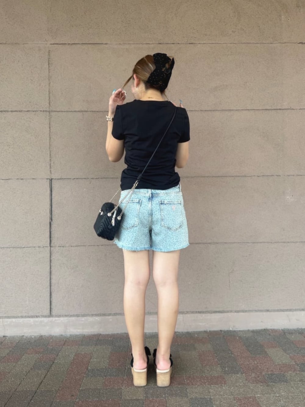 ブルー系のデニムパンツ、ブラック系のTシャツ/カットソー、ブラック系のショルダーバッグを着用したレディースの夏コーディネートの2枚目の写真