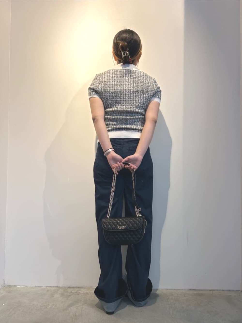 ブラック系のショルダーバッグ、ブラック系のニット/セーター、ブルー系のデニムパンツを着用したレディースの冬コーディネートの2枚目の写真