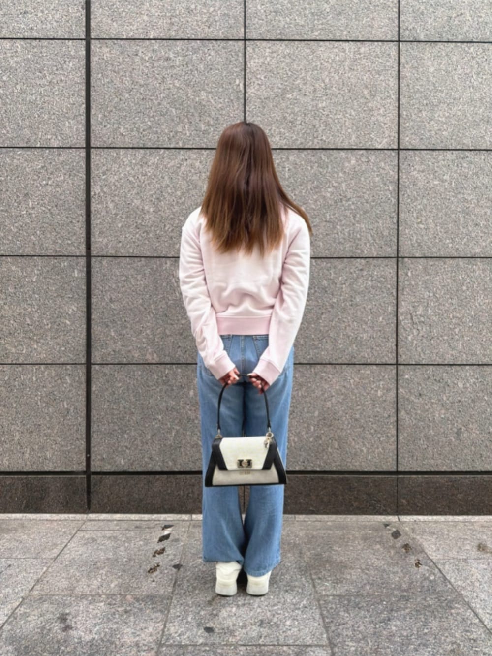 ブルー系のデニムパンツ、ブラック系のショルダーバッグ、ピンク系のスウェットを着用したレディースの冬コーディネートの2枚目の写真