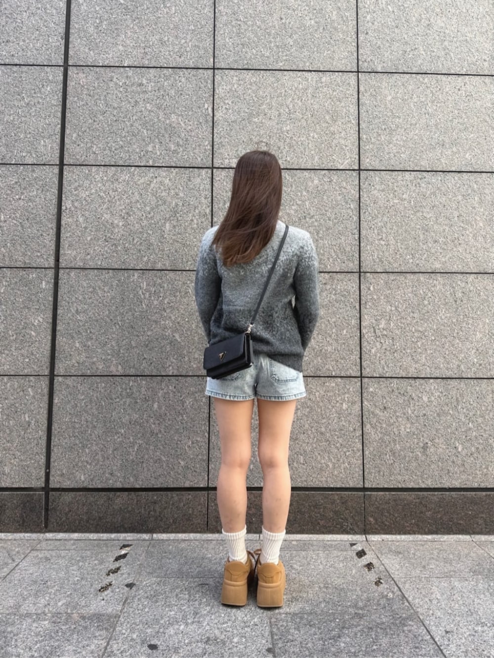 ブラック系のショルダーバッグ、ブルー系のデニムパンツ、グレー系のニット/セーターを着用したレディースの秋コーディネートの2枚目の写真