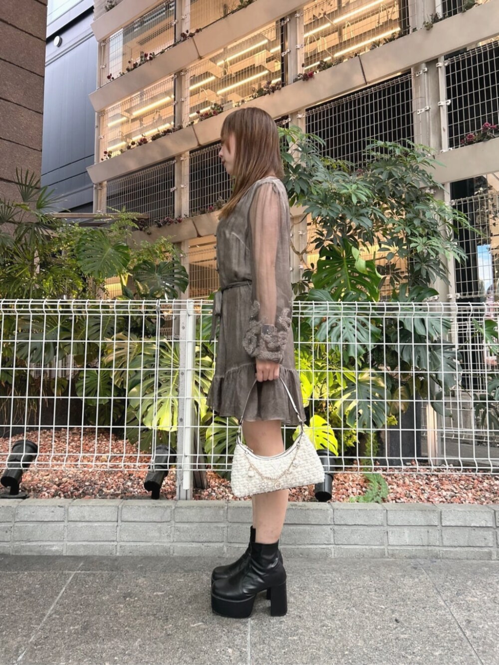 ホワイト系のハンドバッグ、ブラウン系のワンピースを着用したレディースの秋コーディネートの3枚目の写真