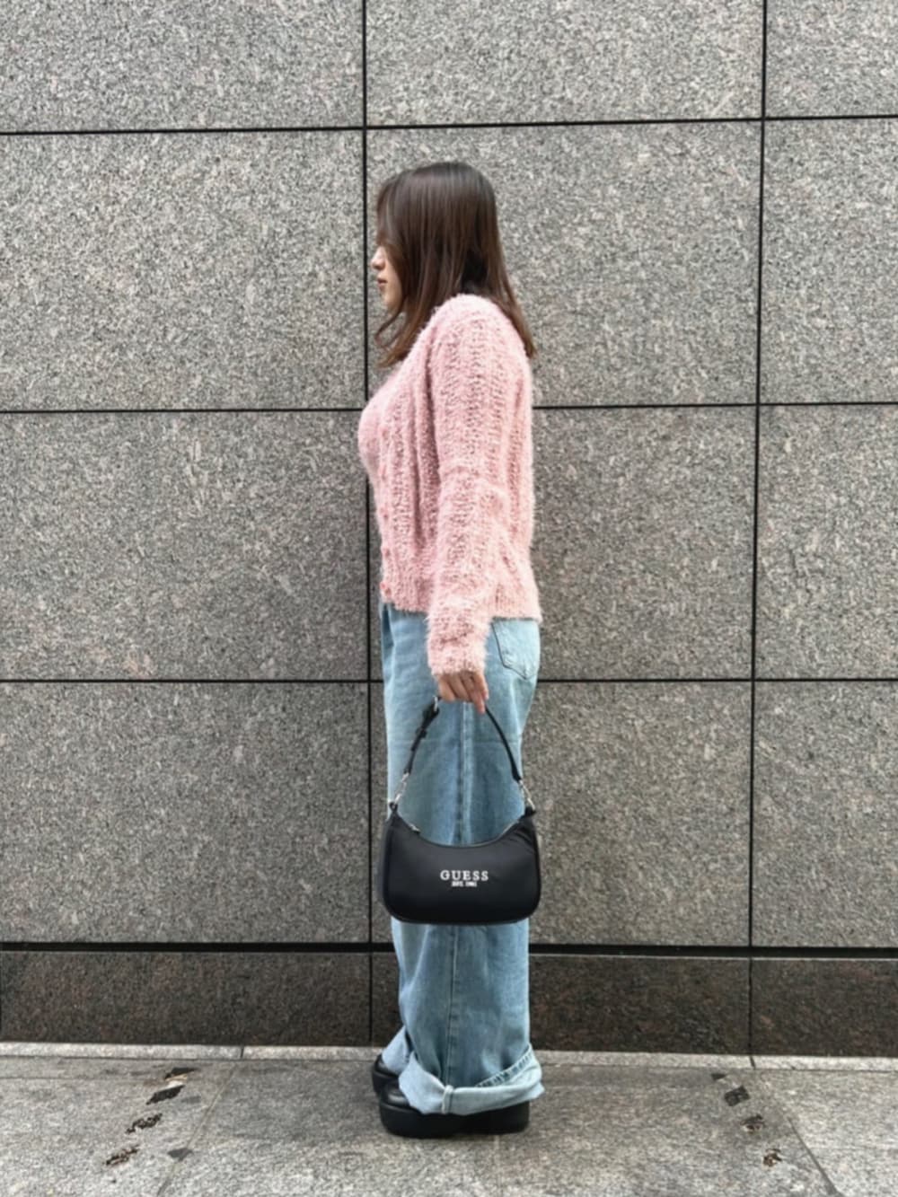 ブラック系のショルダーバッグ、ブルー系のデニムパンツ、ピンク系のカーディガン/ボレロを着用したレディースの冬コーディネートの3枚目の写真