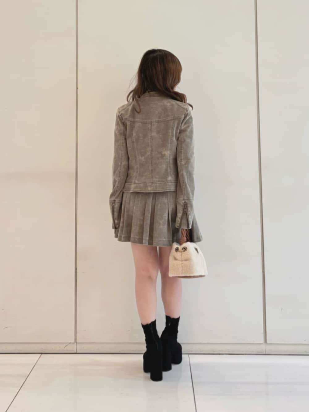 ベージュ系のスカート、ベージュ系のノーカラージャケット、イエロー系のショルダーバッグを着用したレディースの冬コーディネートの2枚目の写真