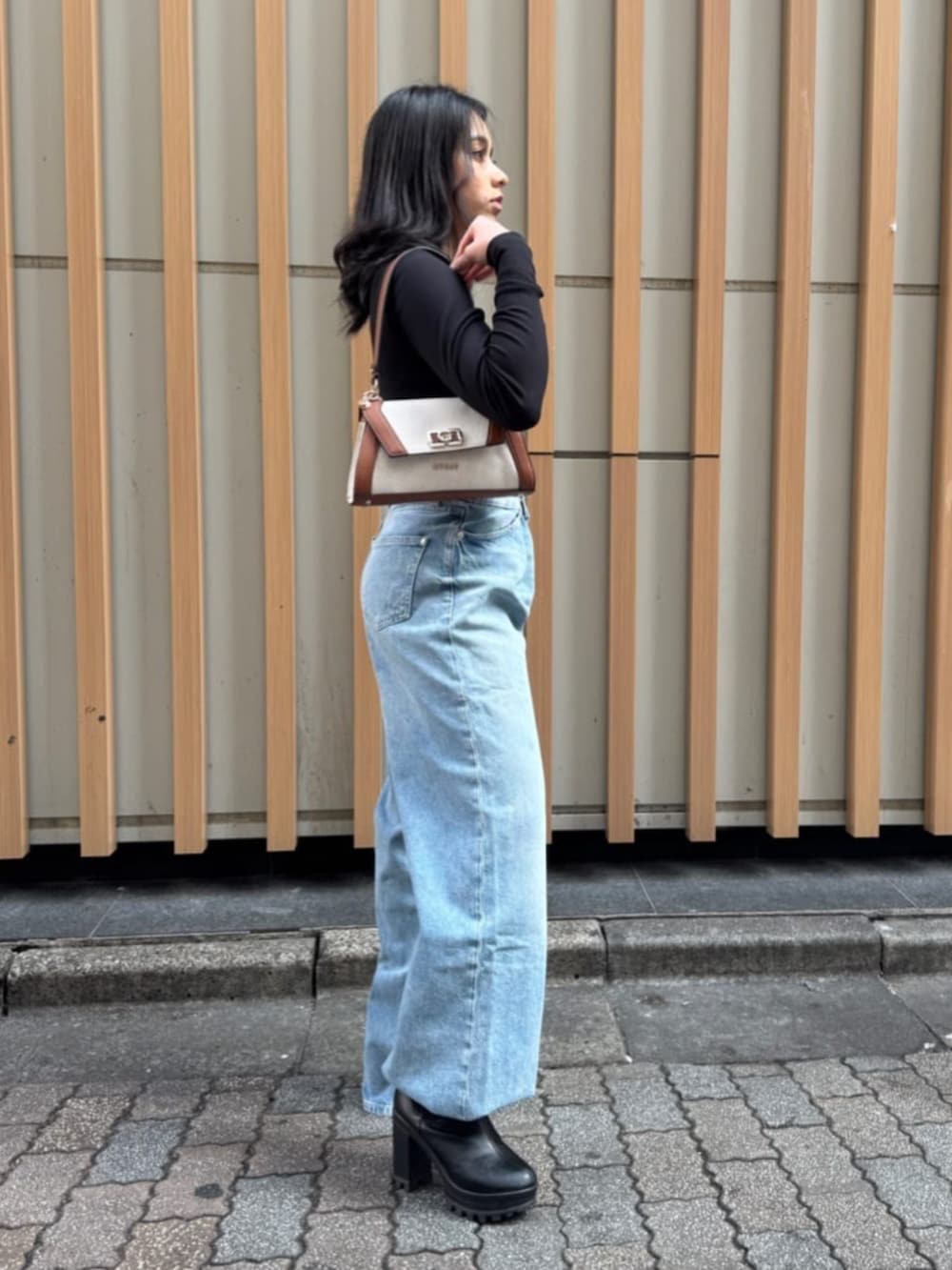 ブルー系のデニムパンツ、ブラック系のTシャツ/カットソー、イエロー系のショルダーバッグを着用したレディースの春コーディネートの4枚目の写真