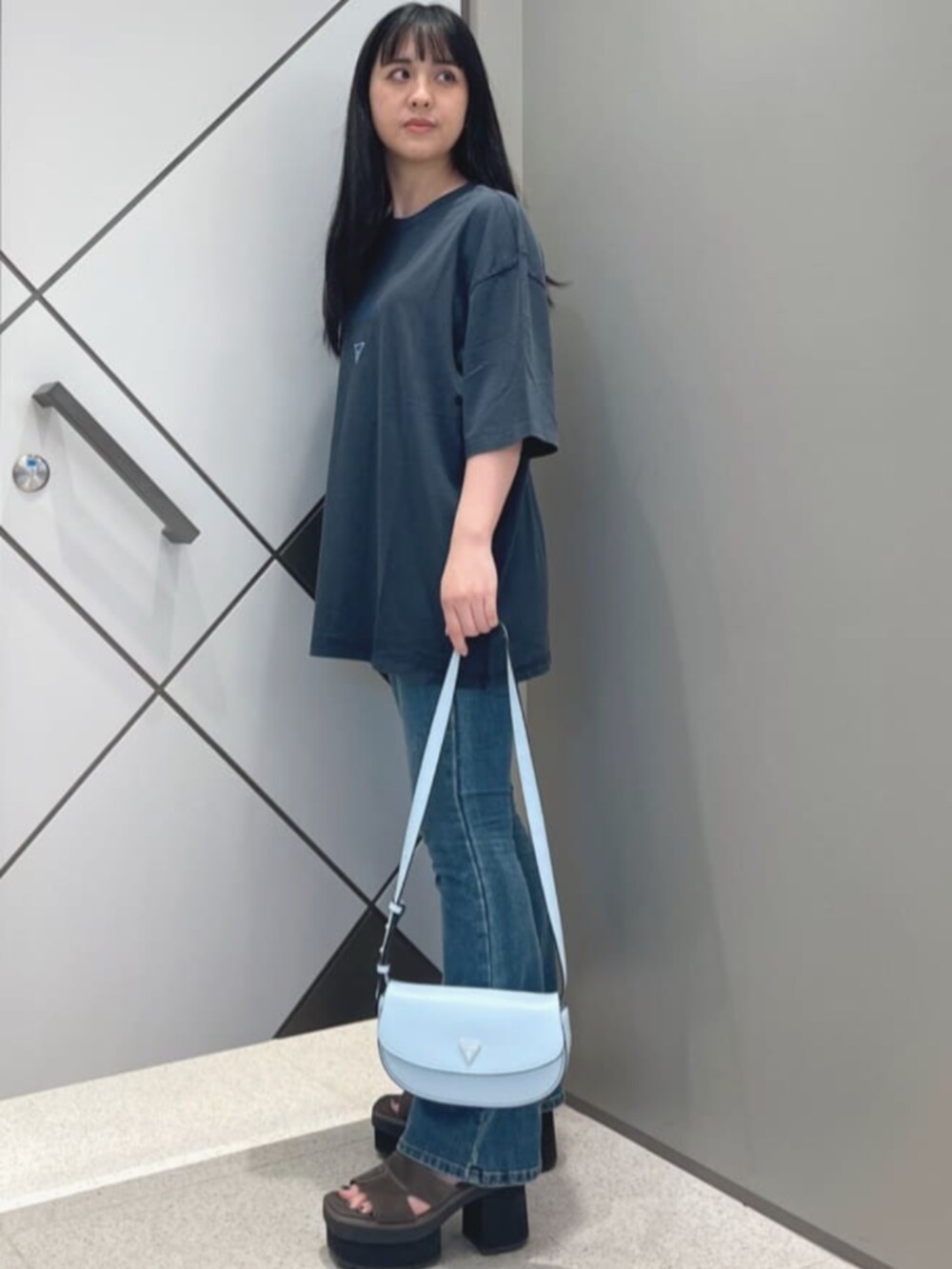 ブルー系のデニムパンツ、ブラック系のTシャツ/カットソー、ブルー系のハンドバッグを着用したレディースの夏コーディネートの3枚目の写真