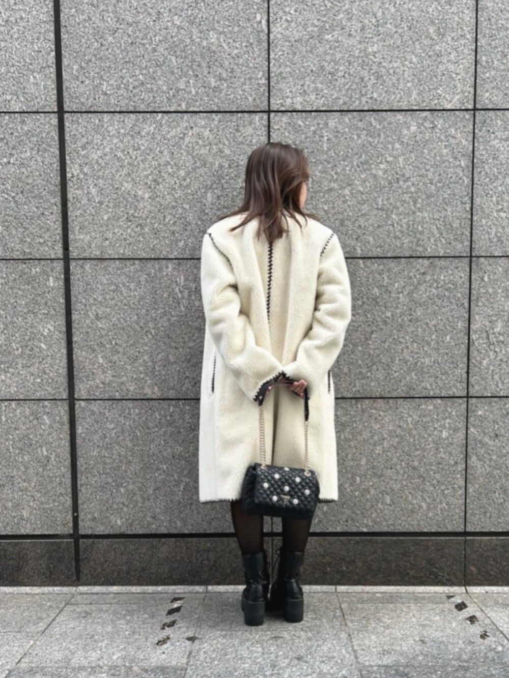 ブラウン系のワンピース、ブラック系のショルダーバッグ、ホワイト系のノーカラージャケットを着用したレディースの秋コーディネートの2枚目の写真