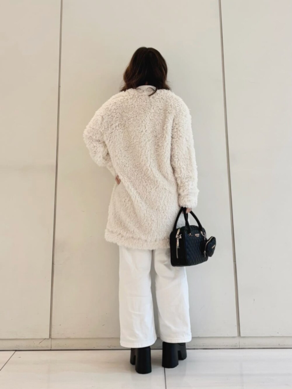ホワイト系のデニムパンツ、ブラック系のハンドバッグ、ホワイト系のカーディガン/ボレロを着用したレディースの冬コーディネートの2枚目の写真