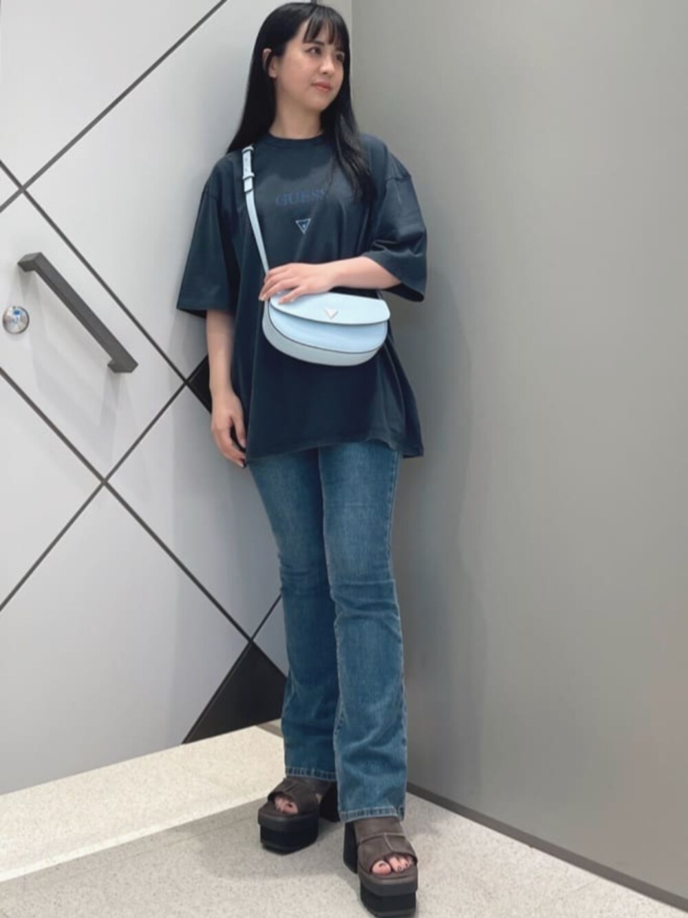 ブルー系のデニムパンツ、ブラック系のTシャツ/カットソー、ブルー系のハンドバッグを着用したレディースの夏コーディネートの4枚目の写真