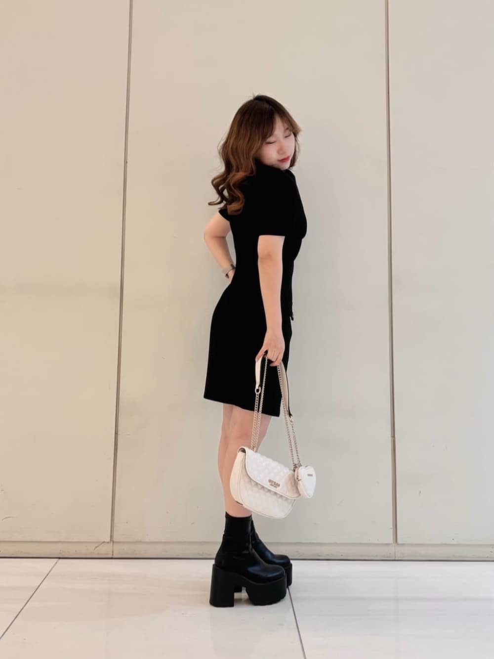 ホワイト系のショルダーバッグ、ブラック系のワンピースを着用したレディースの春コーディネートの3枚目の写真