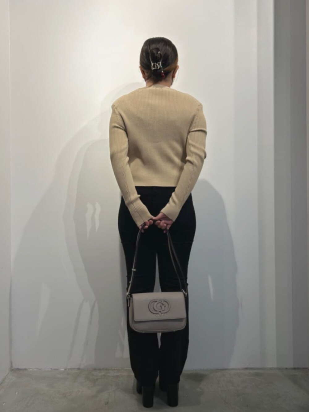 ベージュ系のカーディガン/ボレロ、ブラック系のデニムパンツ、ベージュ系のショルダーバッグを着用したレディースの冬コーディネートの2枚目の写真