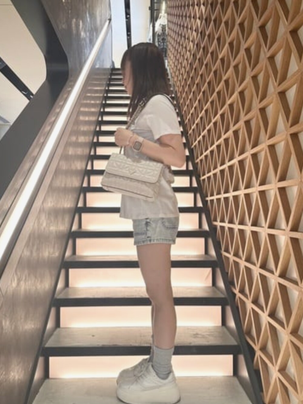 ブルー系のデニムパンツ、ホワイト系のTシャツ/カットソー、ホワイト系のショルダーバッグを着用したレディースの夏コーディネートの3枚目の写真