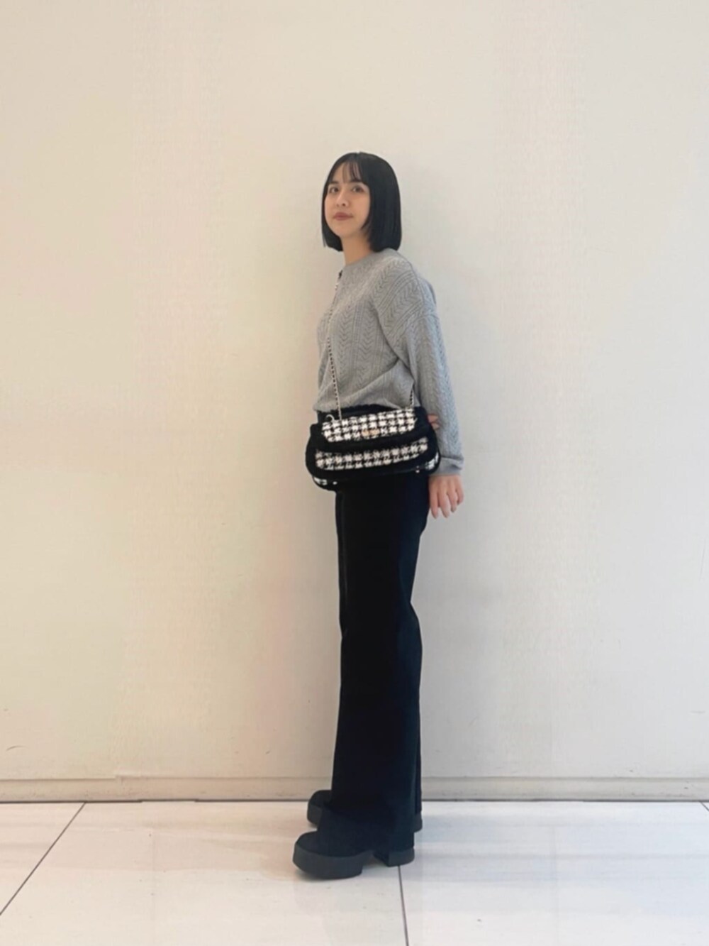 ブラック系のデニムパンツ、グレー系のニット/セーター、ブラック系のショルダーバッグを着用したレディースの冬コーディネートの3枚目の写真