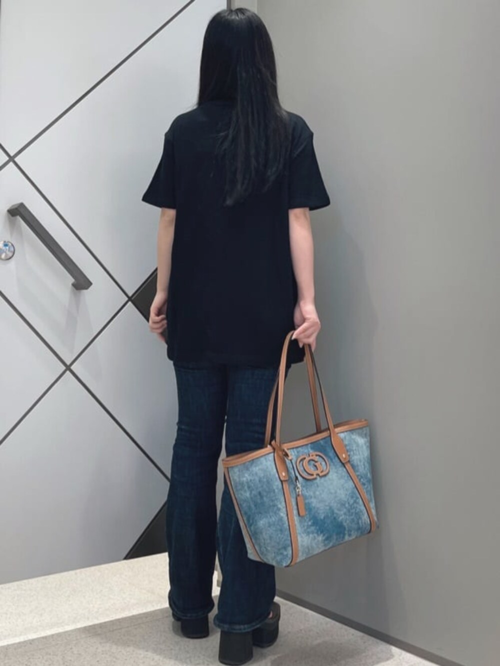 ブルー系のデニムパンツ、ブルー系のトートバッグ、ブラック系のTシャツ/カットソーを着用したレディースの夏コーディネートの2枚目の写真