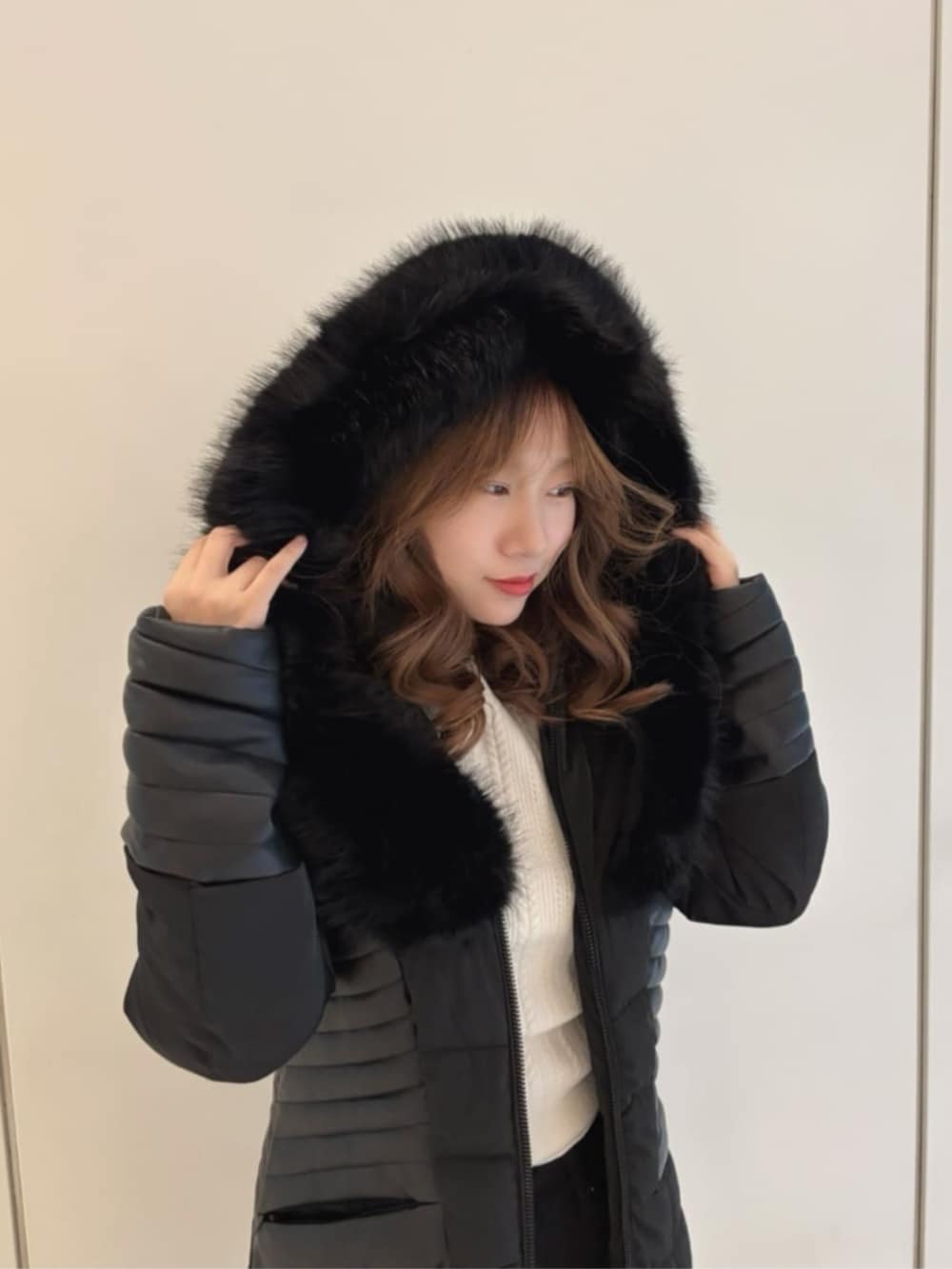 ブラック系のデニムパンツ、ホワイト系のニット/セーター、ブラック系のダウンジャケット/コートを着用したレディースの秋コーディネートの4枚目の写真