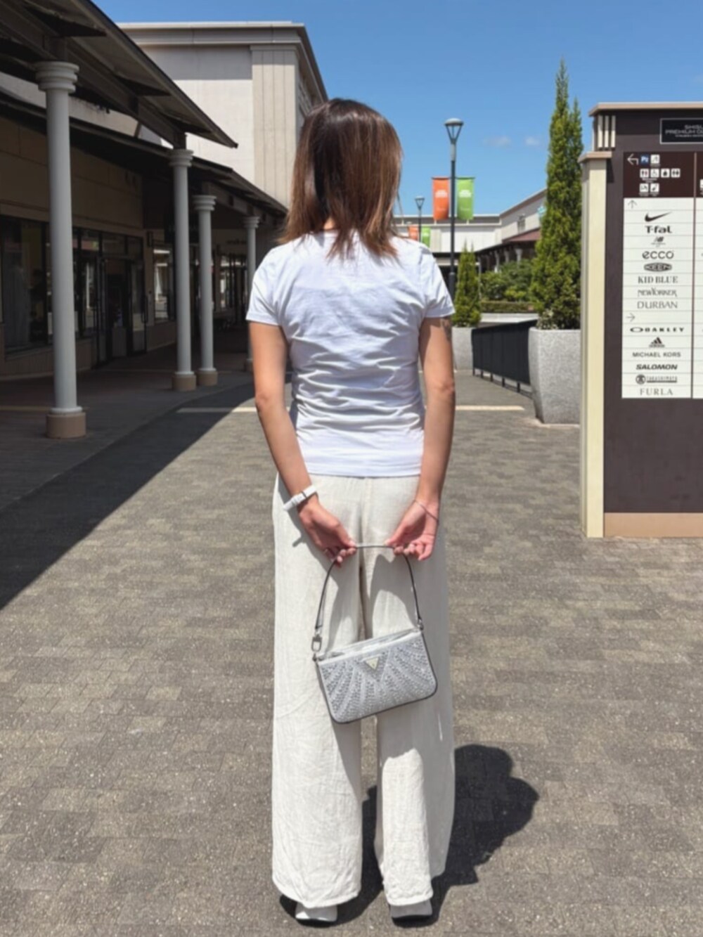 シルバー系のハンドバッグを着用したレディースの夏コーディネートの2枚目の写真
