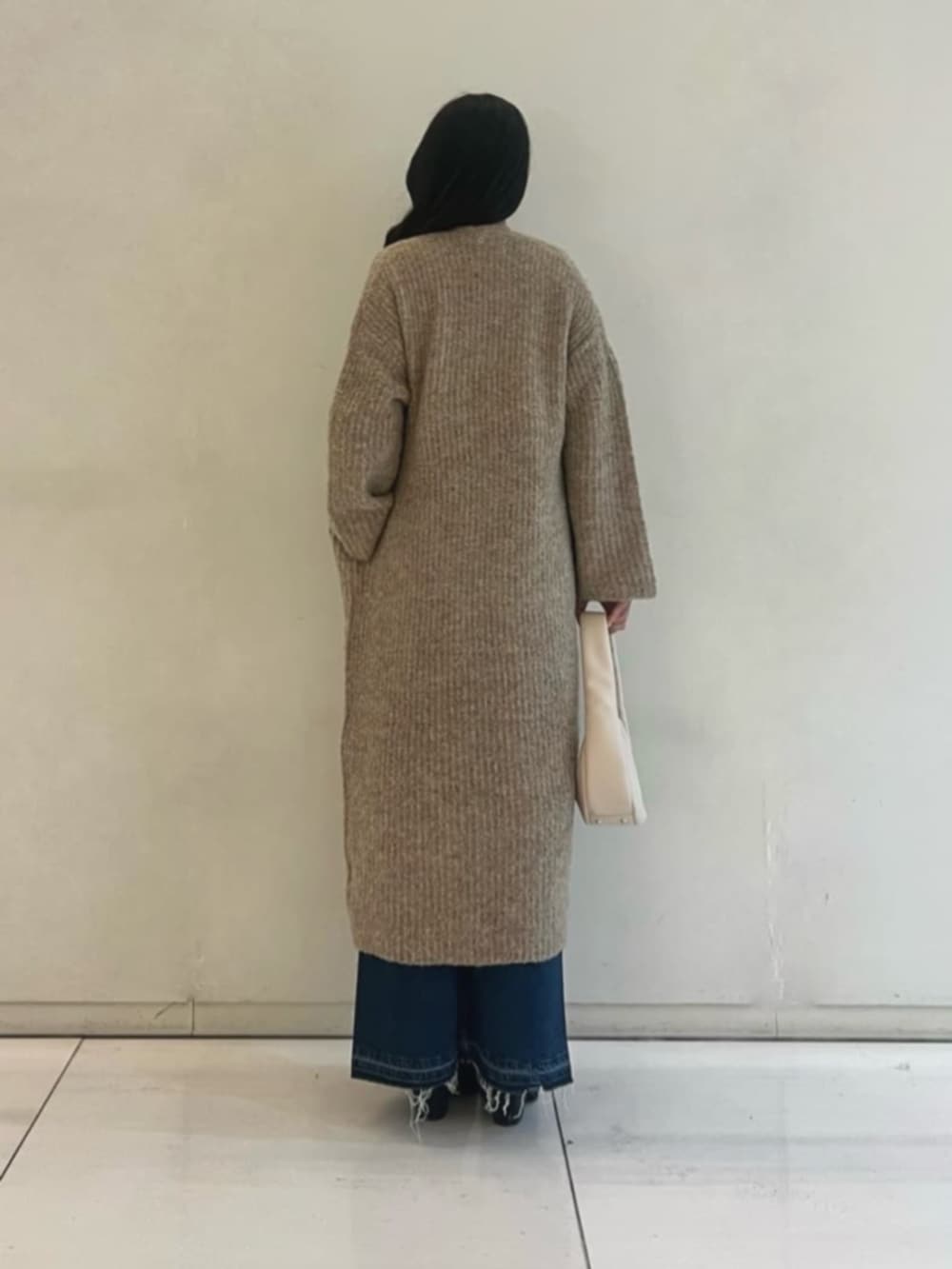 ブルー系のデニムスカート、ホワイト系のニット/セーター、ベージュ系のカーディガン/ボレロを着用したレディースの秋コーディネートの2枚目の写真