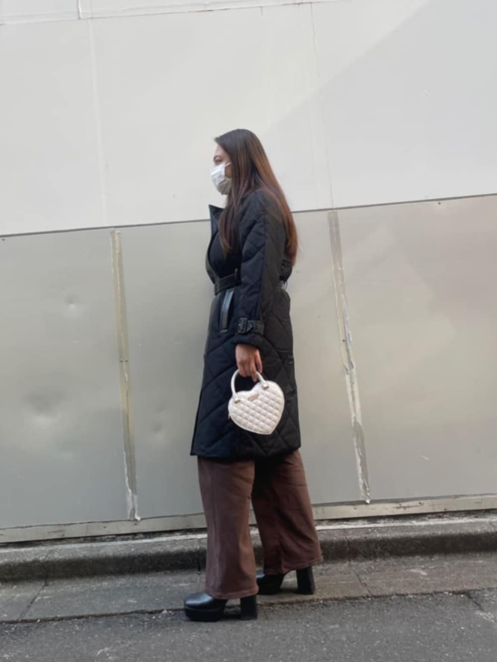 ブラック系のトレンチコート、ホワイト系のショルダーバッグを着用したレディースの冬コーディネートの3枚目の写真