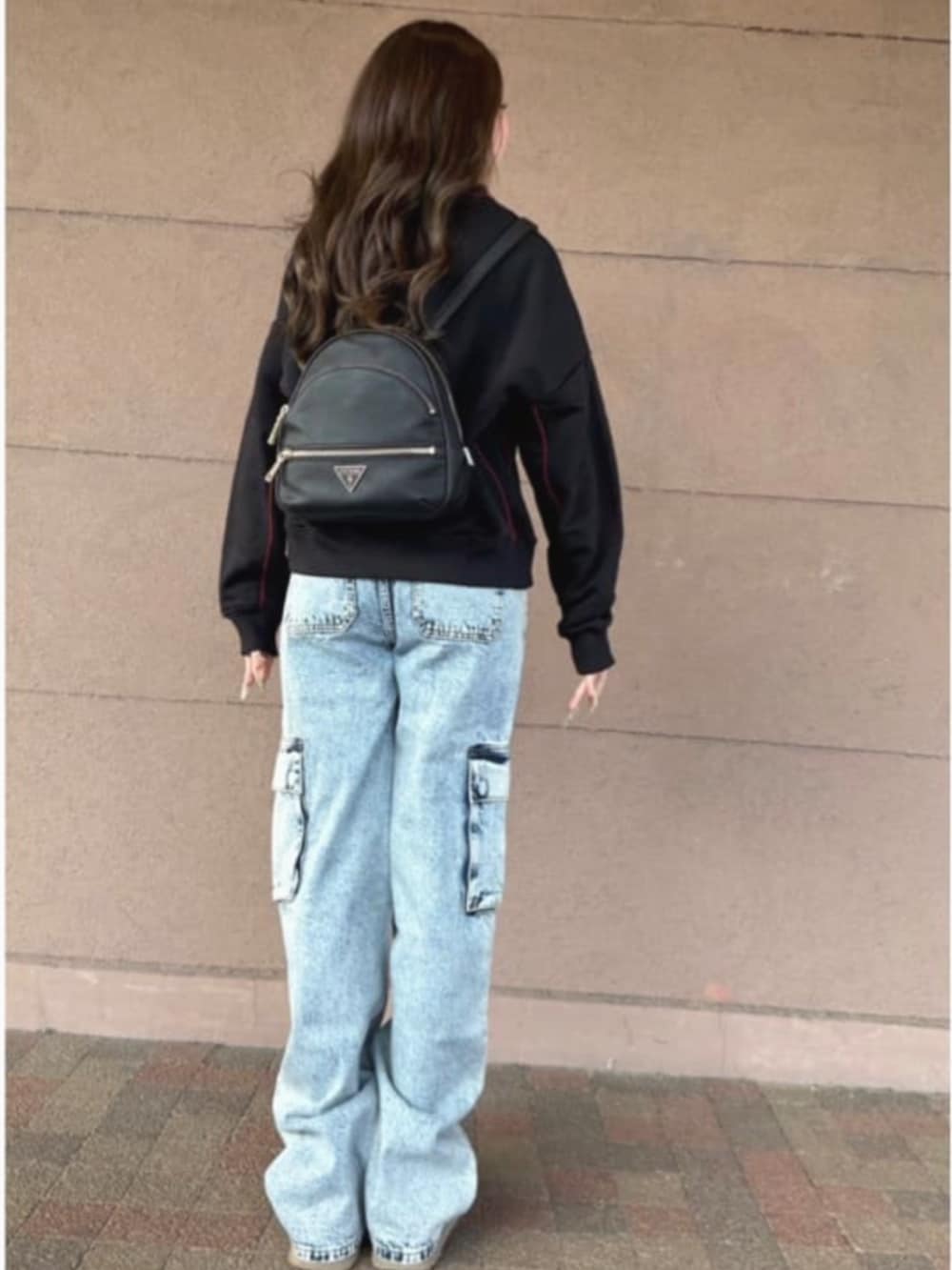 ブラック系のバックパック/リュック、ブルー系のデニムパンツ、ブラック系のスウェットを着用したレディースの冬コーディネートの2枚目の写真