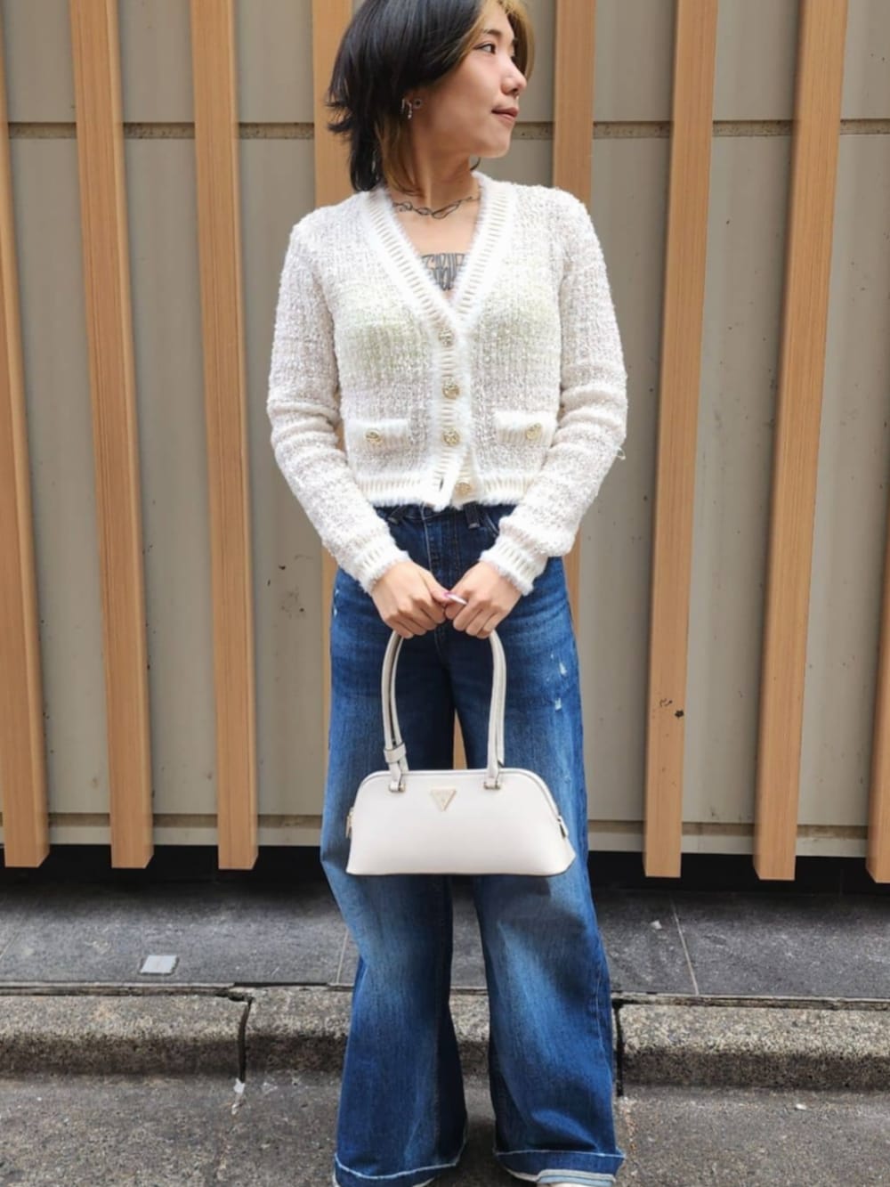 ホワイト系のショルダーバッグ、ブルー系のデニムパンツ、ホワイト系のカーディガン/ボレロを着用したレディースの冬コーディネートの5枚目の写真