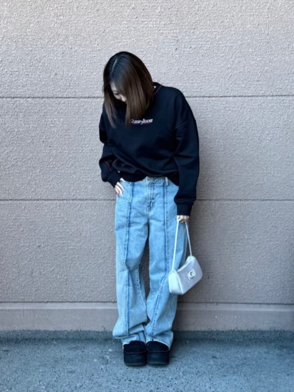 ブラック系のスウェット、ブルー系のデニムパンツを着用したレディースの春コーディネートの2枚目の写真