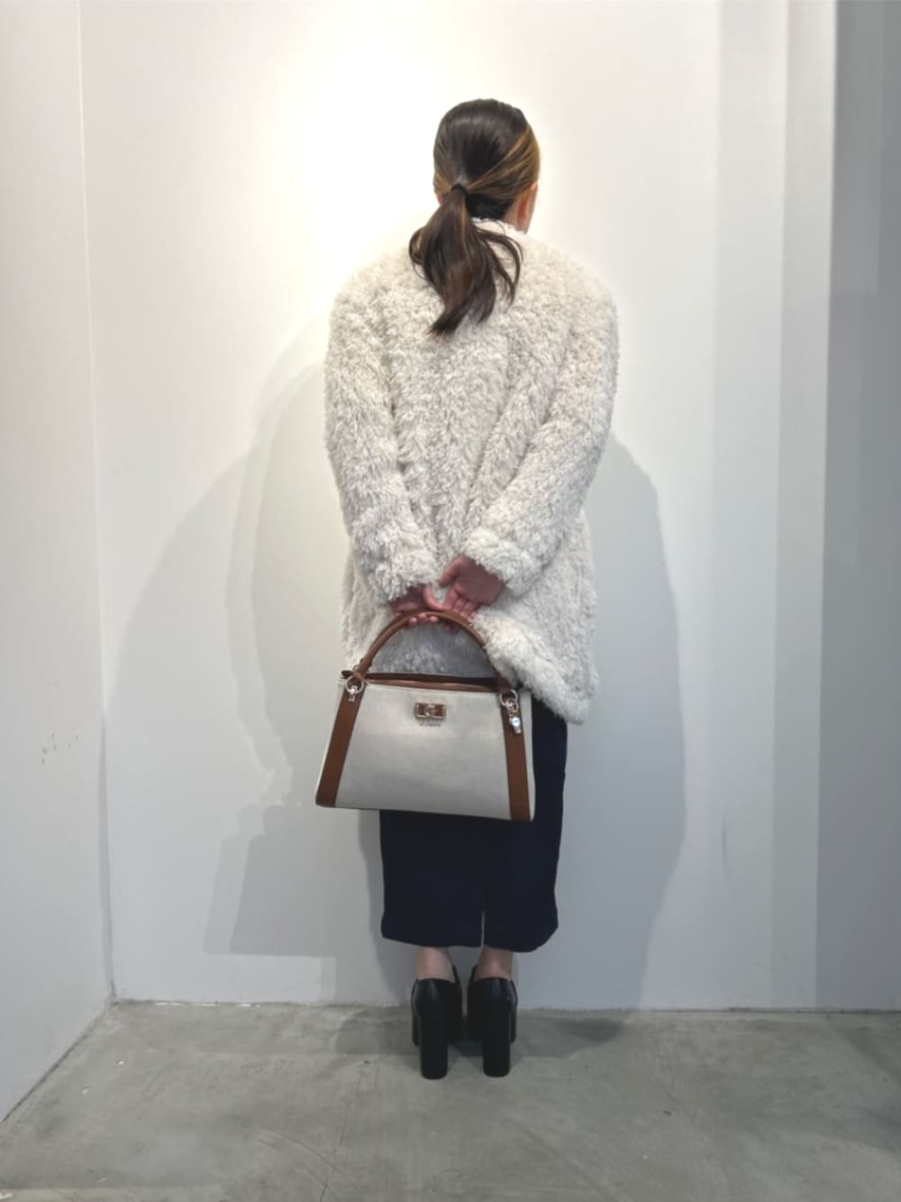 イエロー系のハンドバッグ、ホワイト系のカーディガン/ボレロ、ブルー系のワンピースを着用したレディースの冬コーディネートの2枚目の写真