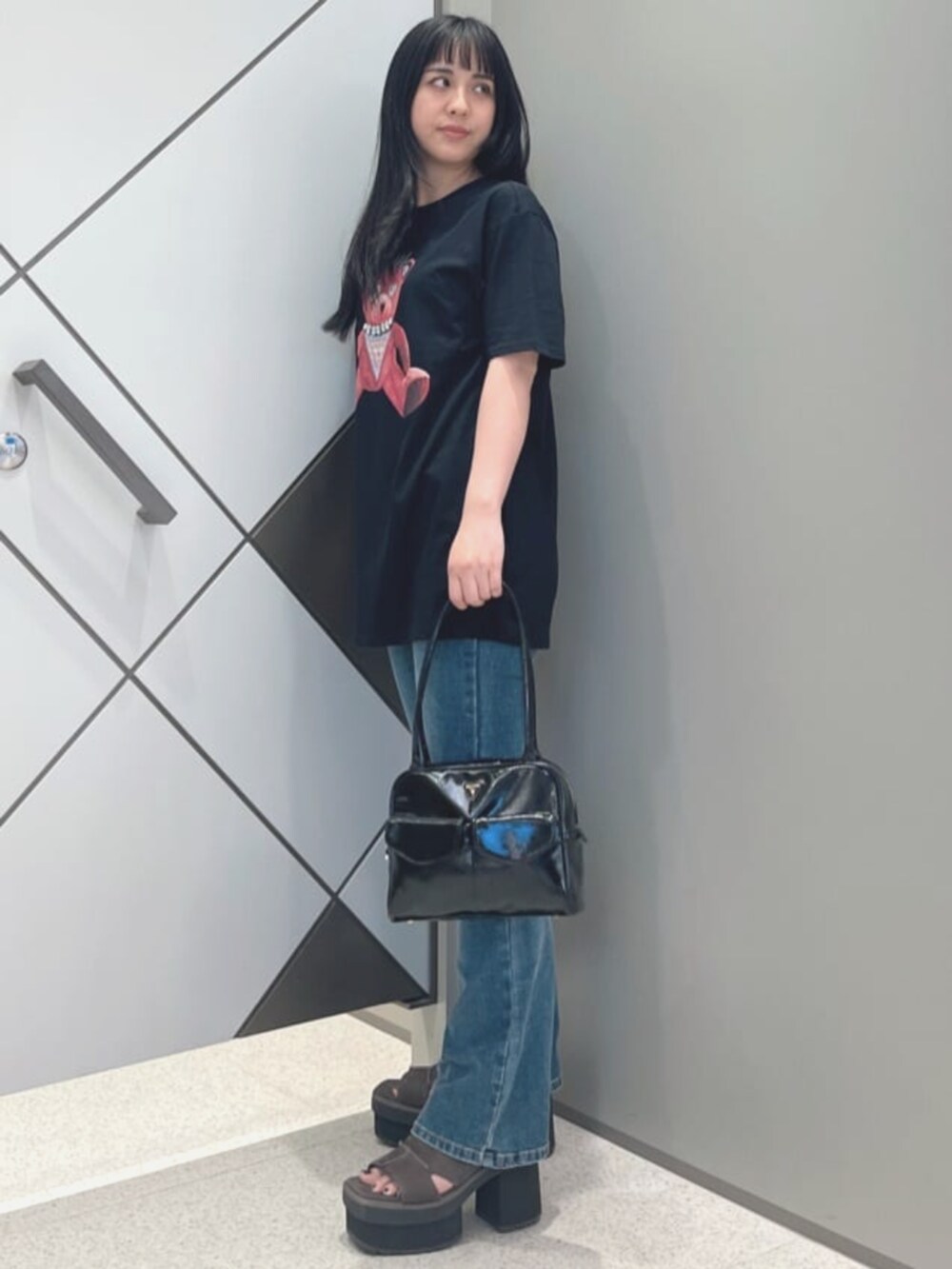 ブルー系のデニムパンツ、ブラック系のTシャツ/カットソー、ブラック系のショルダーバッグを着用したレディースの夏コーディネートの3枚目の写真