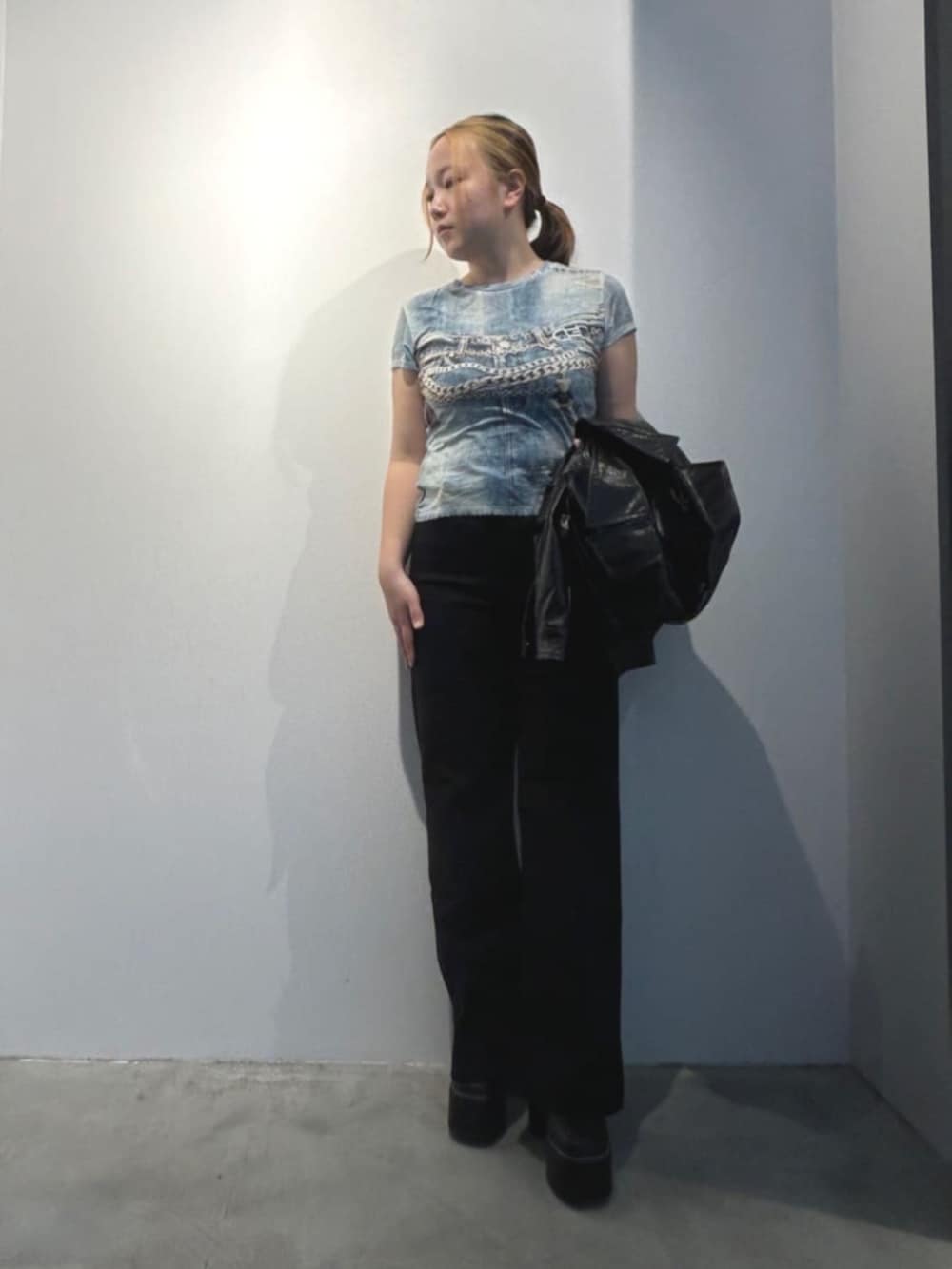 ブラック系のデニムパンツ、ベージュ系のショルダーバッグ、ブラック系のカバーオールを着用したレディースの春コーディネートの4枚目の写真