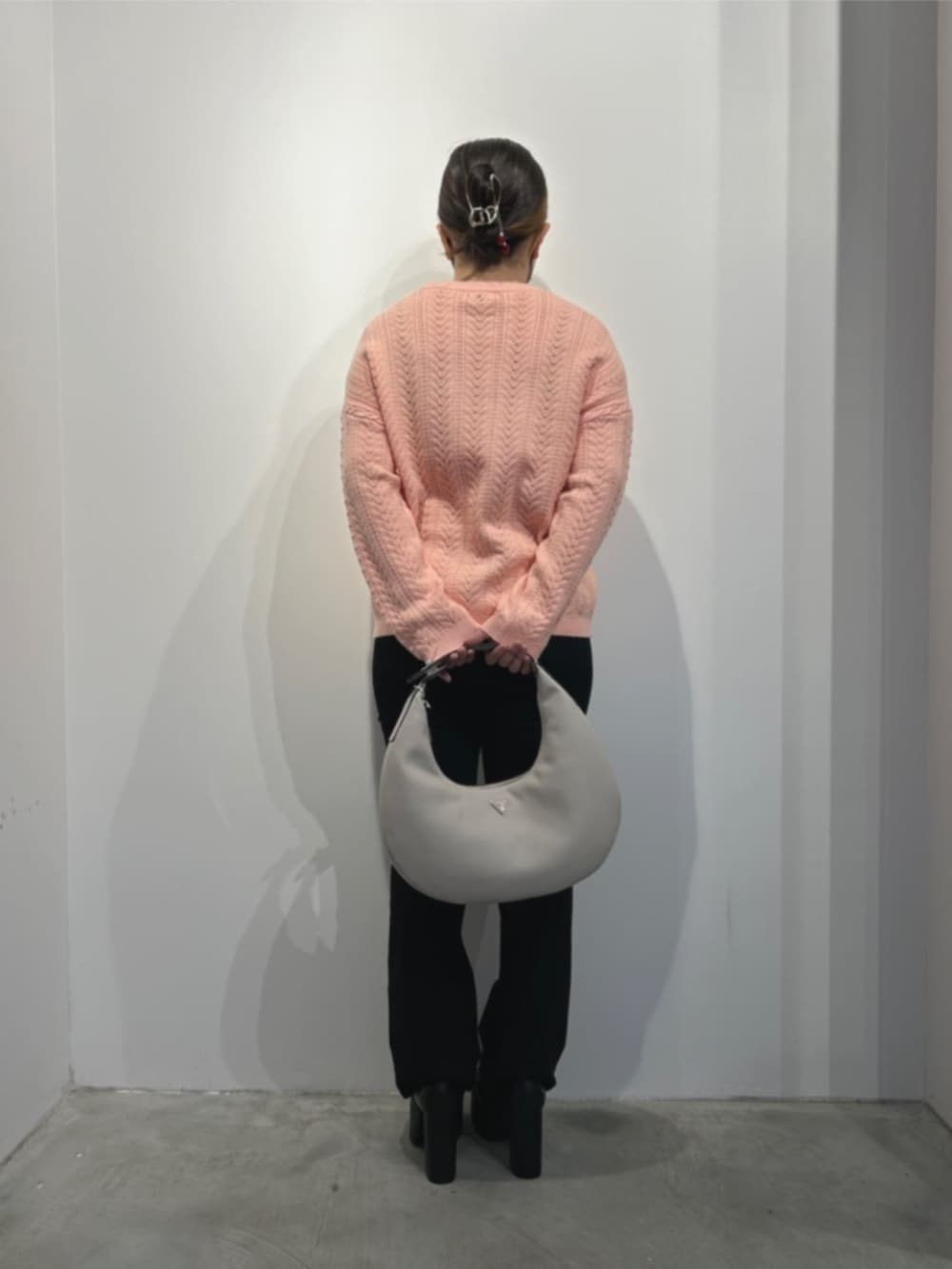 ブラック系のデニムパンツ、ベージュ系のハンドバッグ、ピンク系のニット/セーターを着用したレディースの冬コーディネートの2枚目の写真