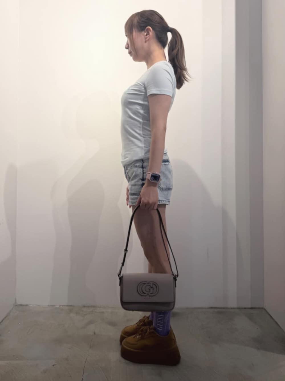 ブルー系のデニムパンツ、グリーン系のTシャツ/カットソー、ベージュ系のショルダーバッグを着用したレディースの冬コーディネートの3枚目の写真