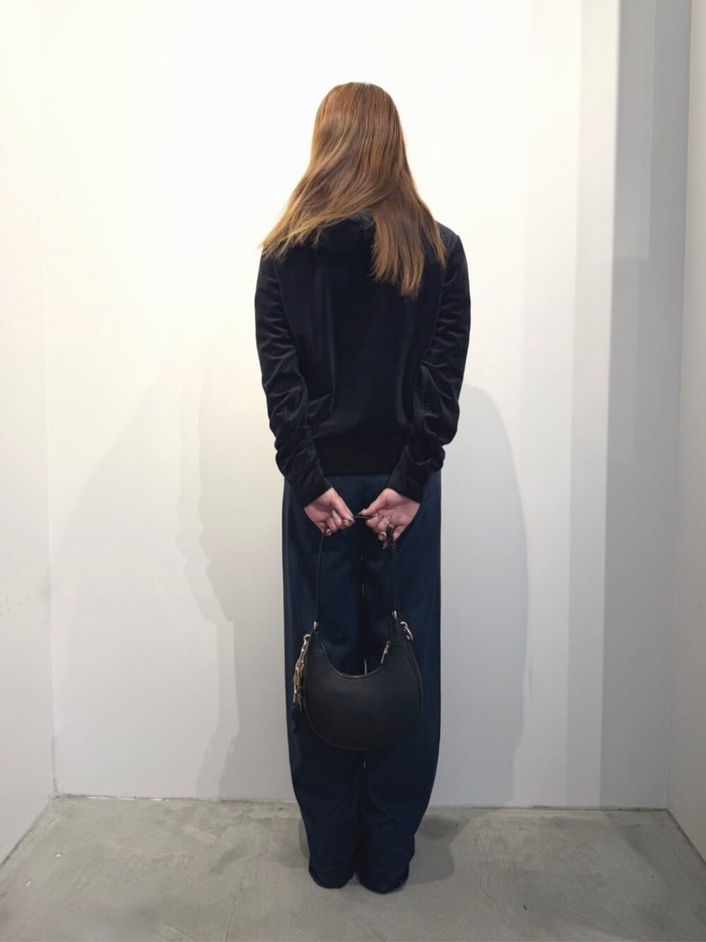 ブラック系のショルダーバッグ、ブルー系のデニムパンツ、ブラック系のパーカーを着用したレディースの春コーディネートの2枚目の写真