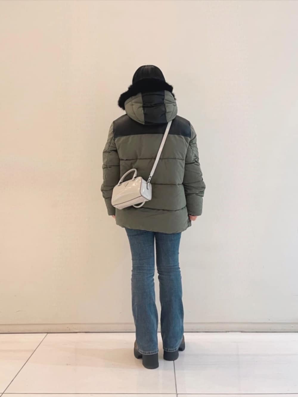 ブルー系のデニムパンツ、ホワイト系のニット/セーター、グリーン系のその他アウターを着用したレディースの冬コーディネートの2枚目の写真