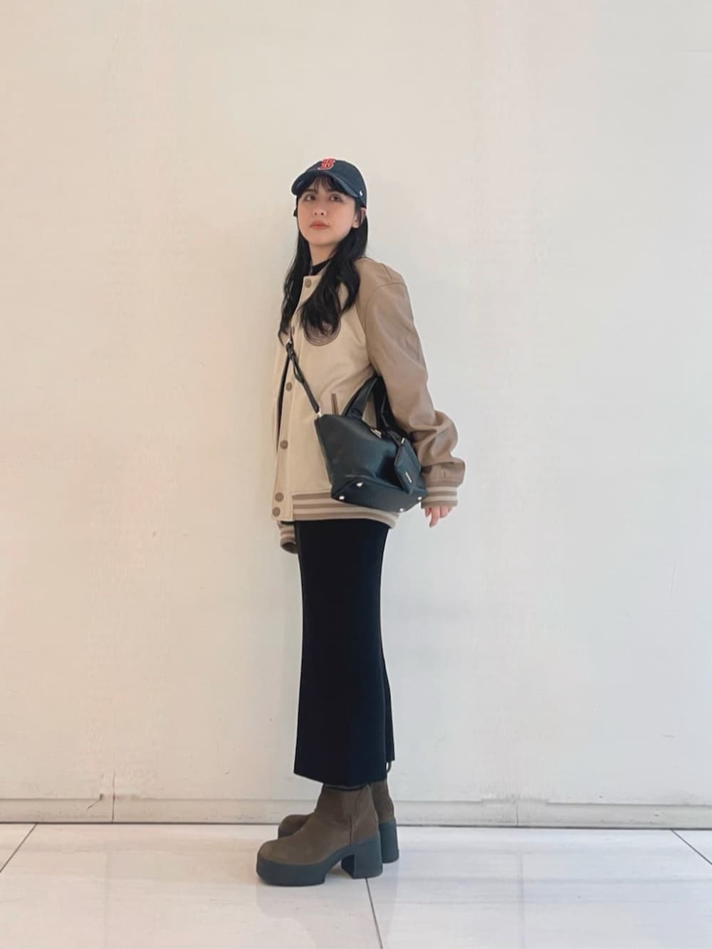 ブラック系のワンピース、ブラック系のトートバッグ、ベージュ系のスタジャンを着用したレディースの秋コーディネートの3枚目の写真