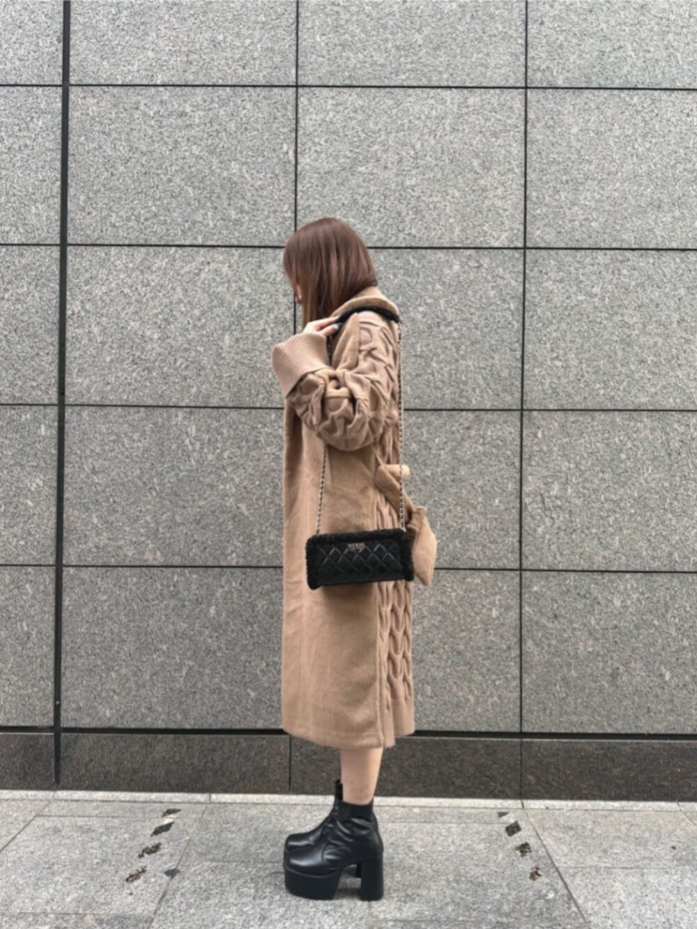 ベージュ系のムートンコート、ブラック系のショルダーバッグ、ホワイト系のワンピースを着用したレディースの冬コーディネートの3枚目の写真