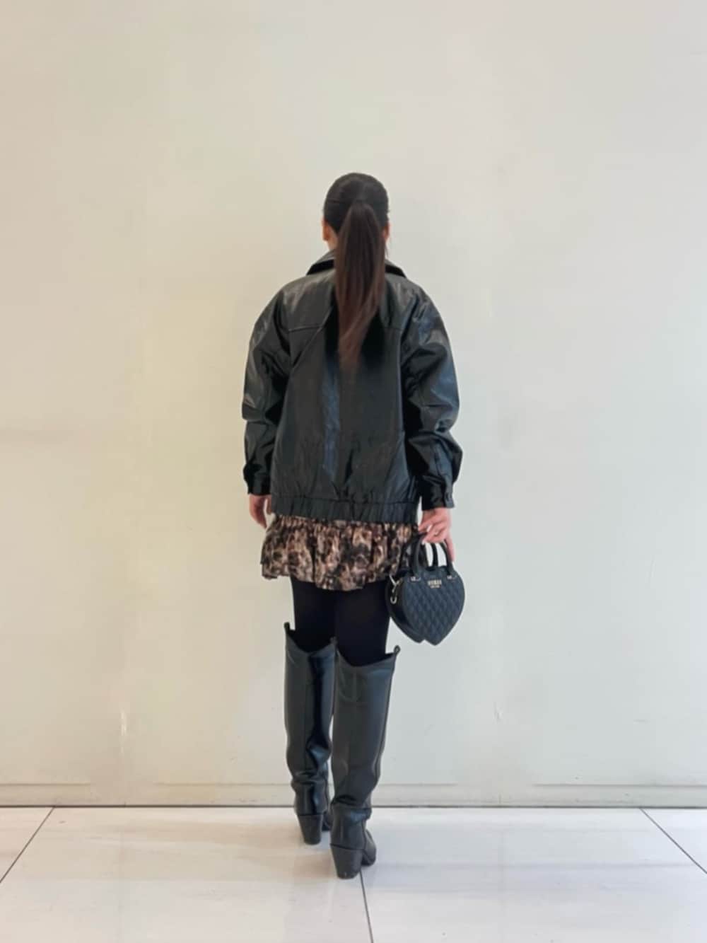 ブラック系のショルダーバッグ、ブラウン系のワンピース、ブラック系のカバーオールを着用したレディースの冬コーディネートの2枚目の写真